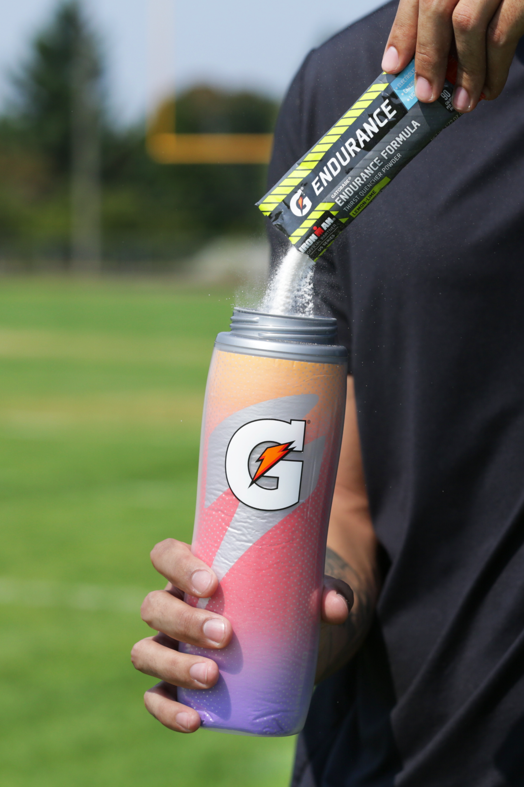 Athlete pouring Gatorade endurance powder into a Purple Flame Insulated Squeeze Bottle