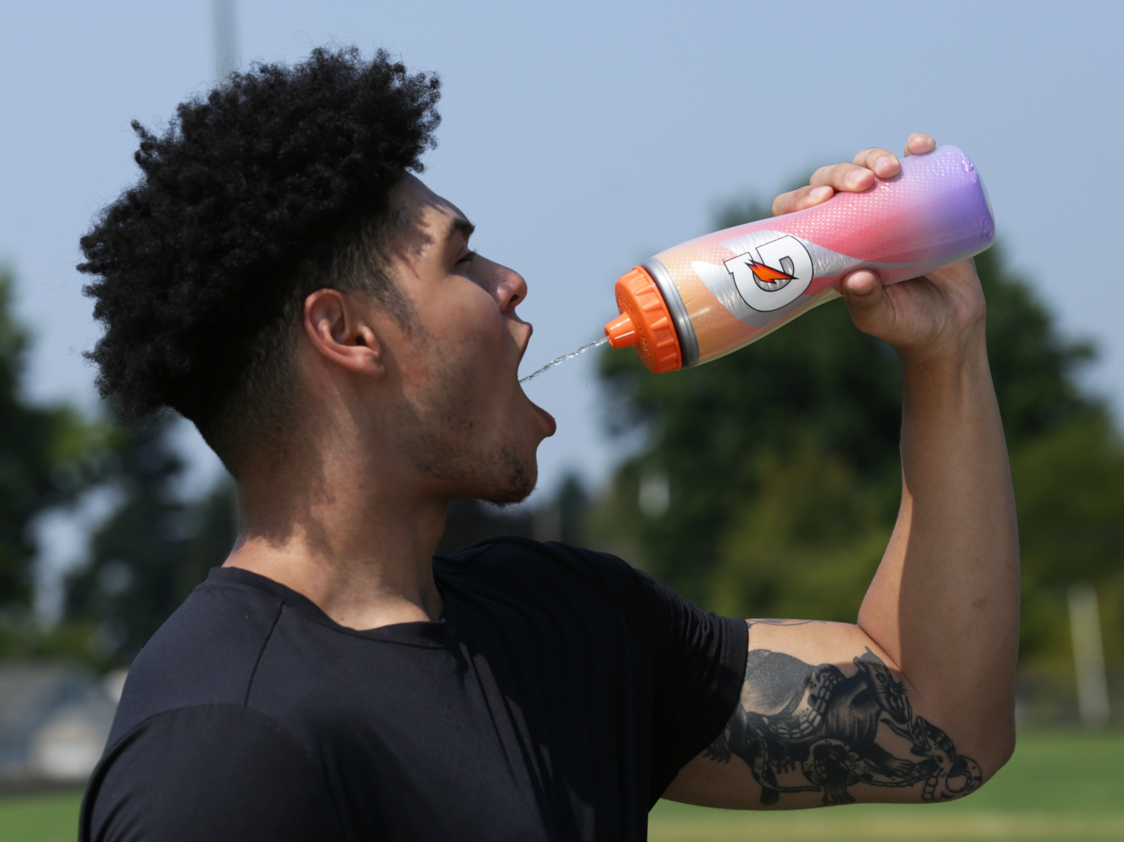 Athlete drinking Gatorade from a Purple Flame Insulated Squeeze Bottle