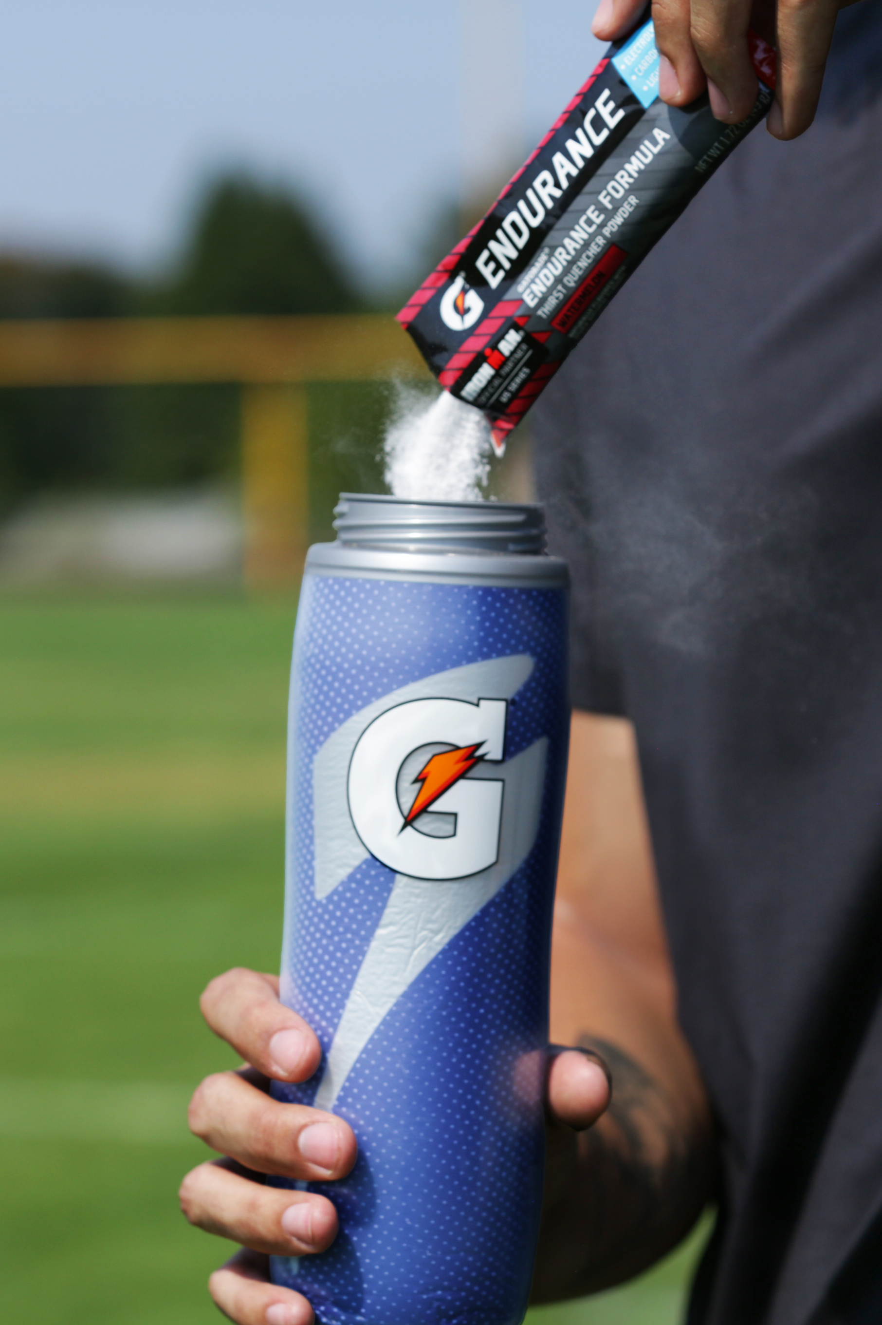 Athlete pouring Gatorade endurance powder into a Royal Blue Insulated Squeeze Bottle