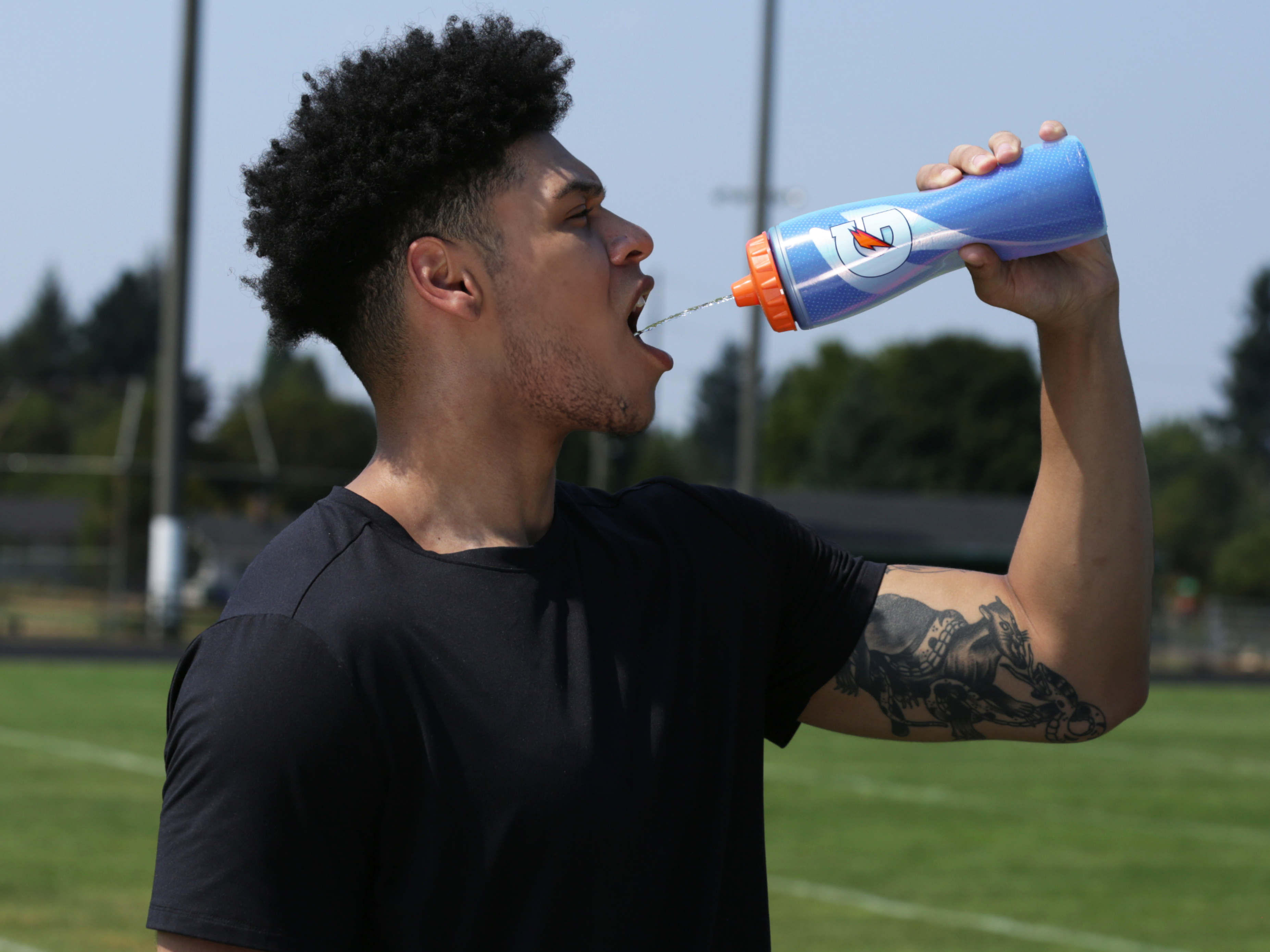 Athlete drinking Gatorade from a Royal Blue Insulated Squeeze Bottle