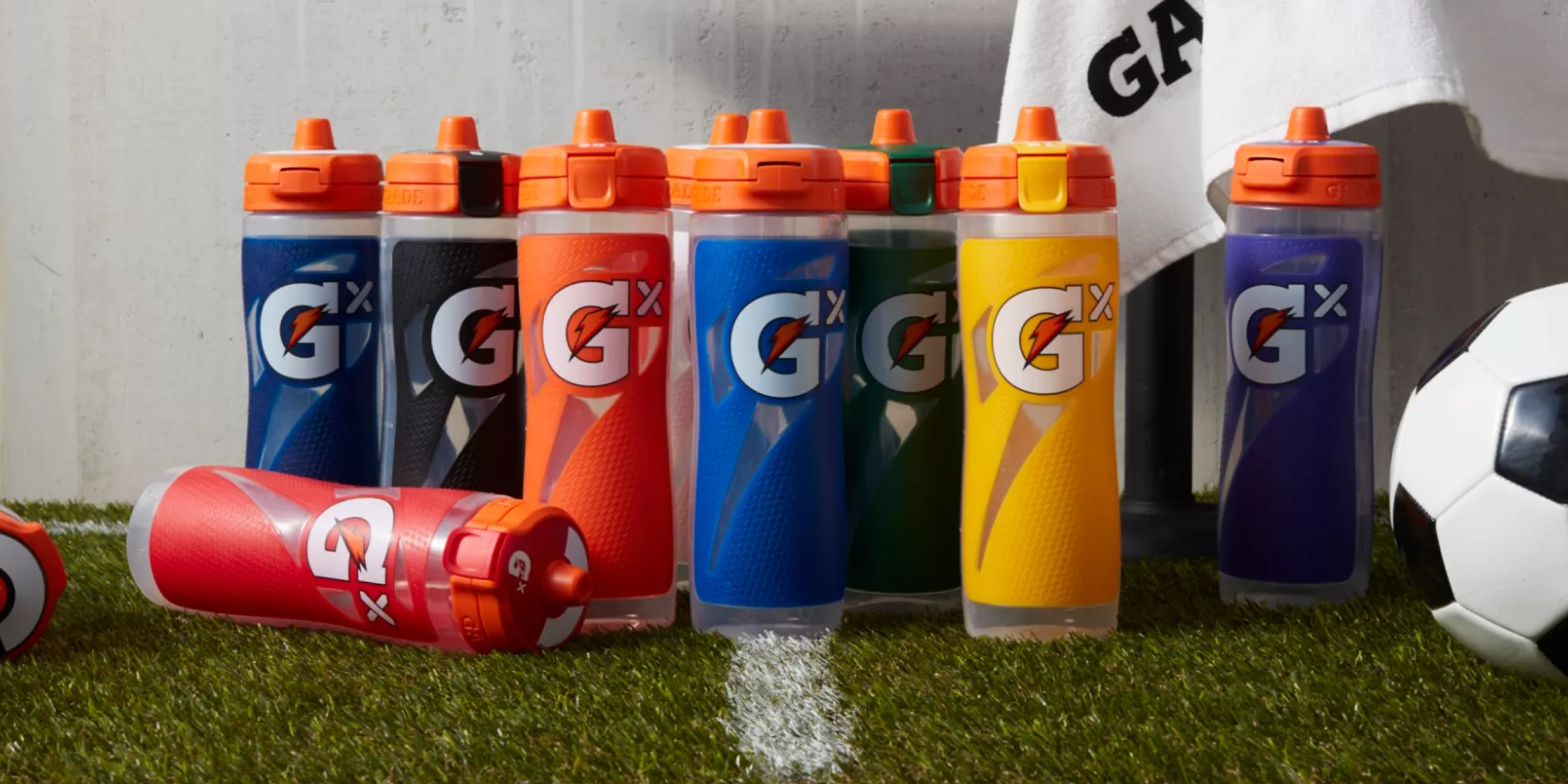 Gx Bottles in various colors on a soccer field