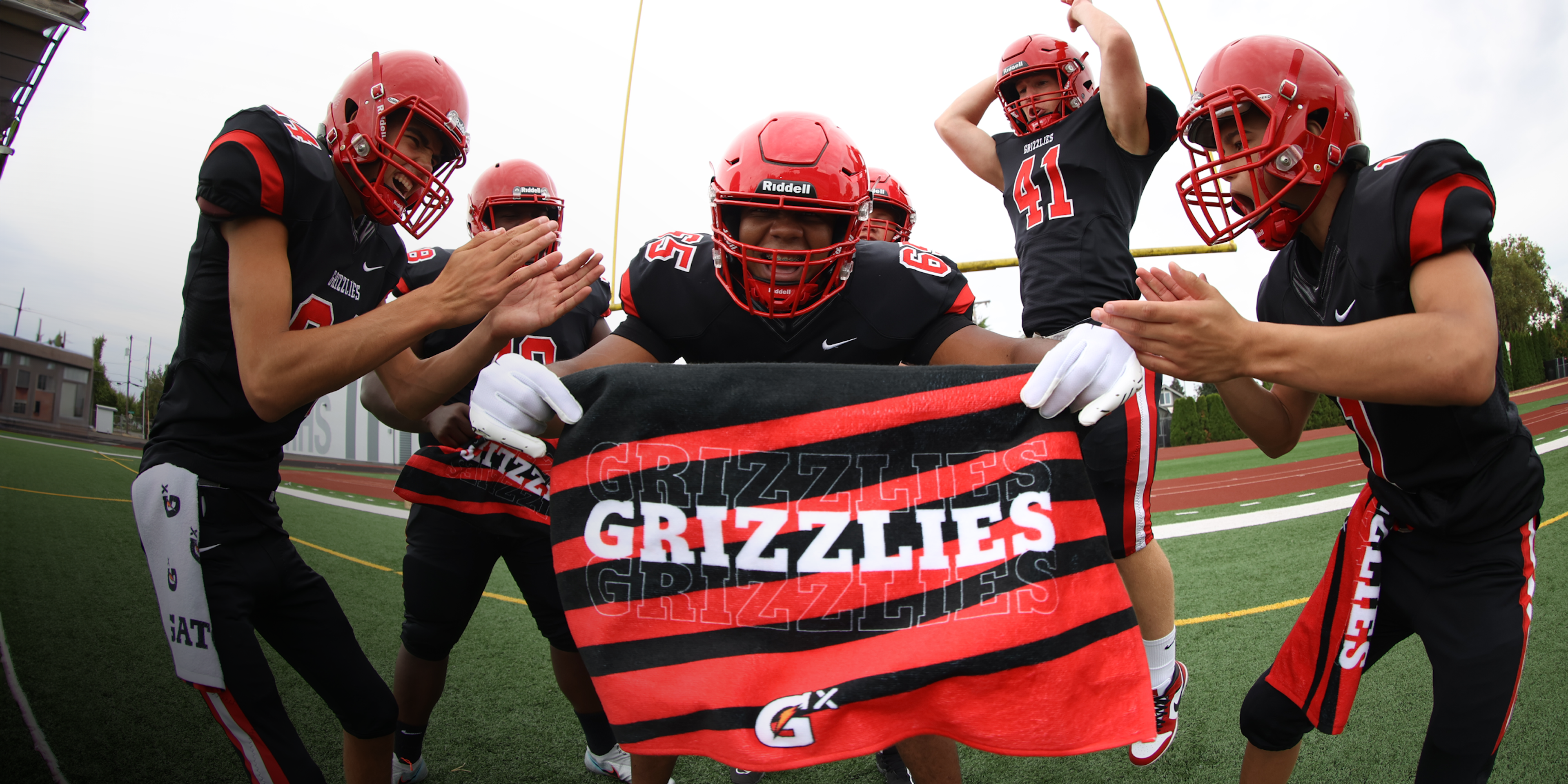 Football team celebrating holding red and black customized towel