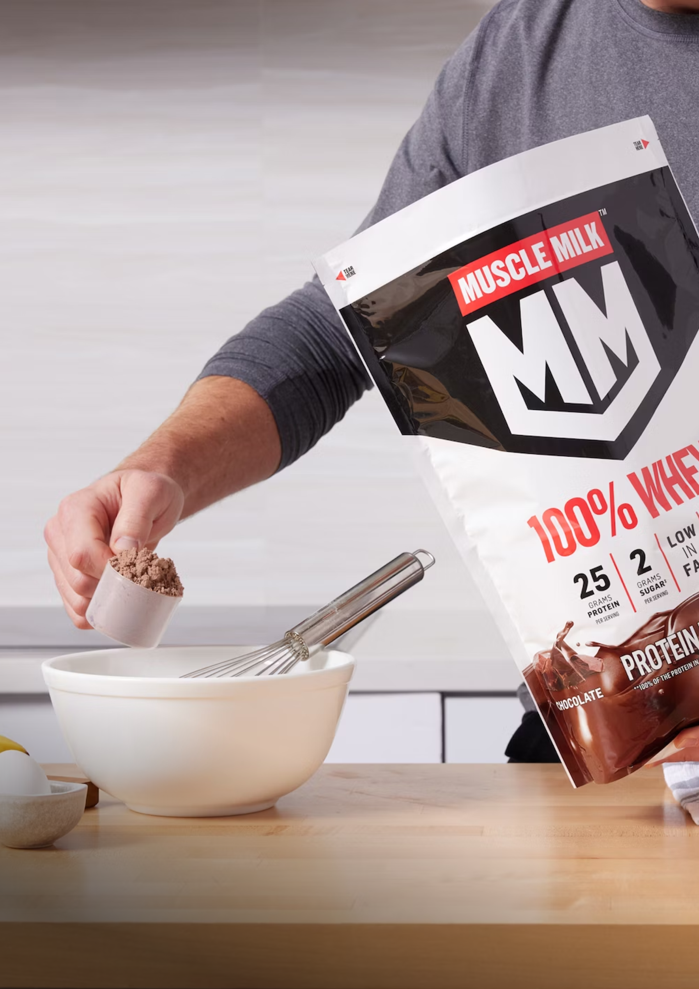 Muscle milk 100% whey protein powder being scooped into bowl