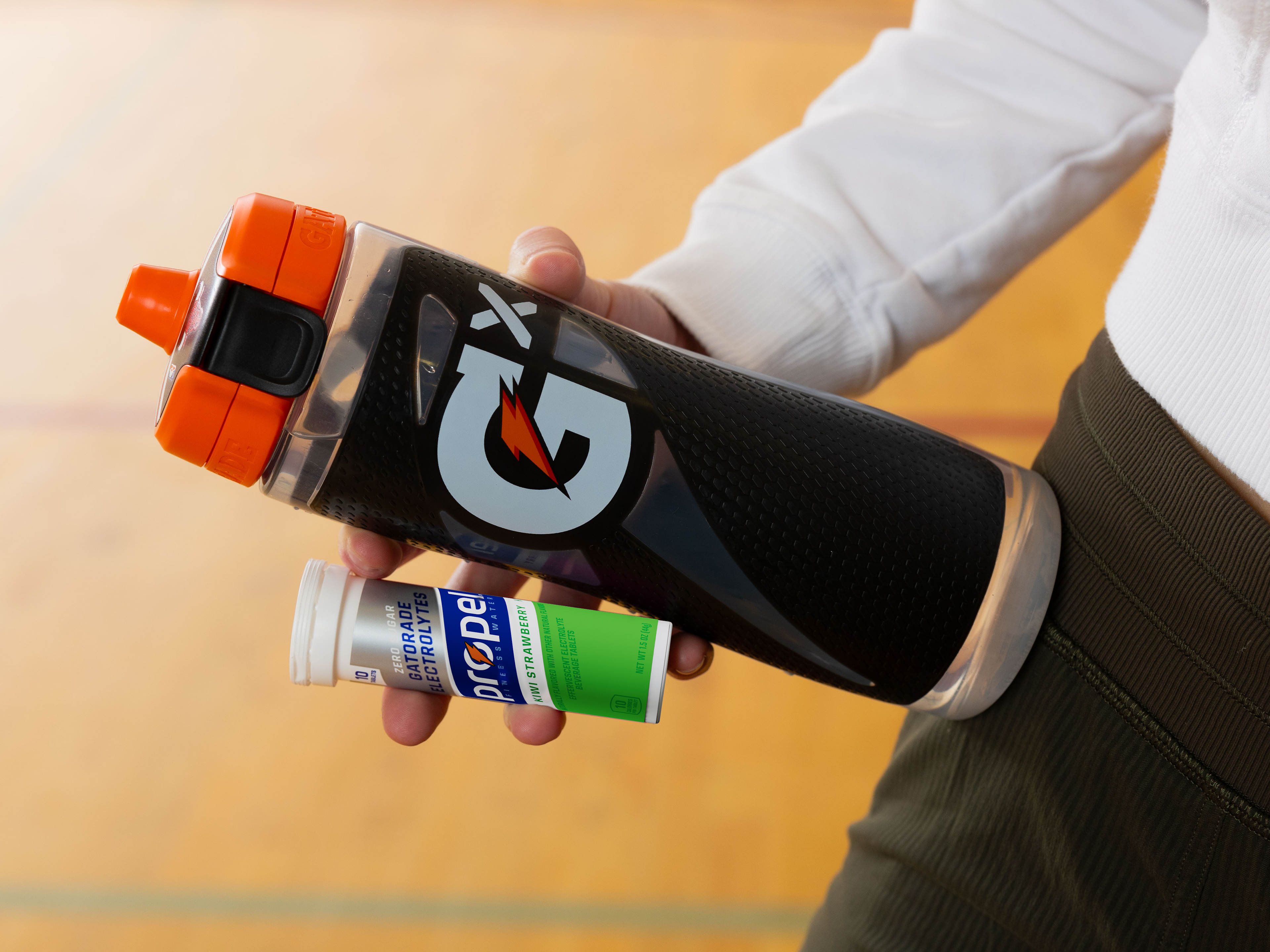 Athlete holding Propel Tablet Kiwi Strawberry pack with a Gx Squeeze bottle.