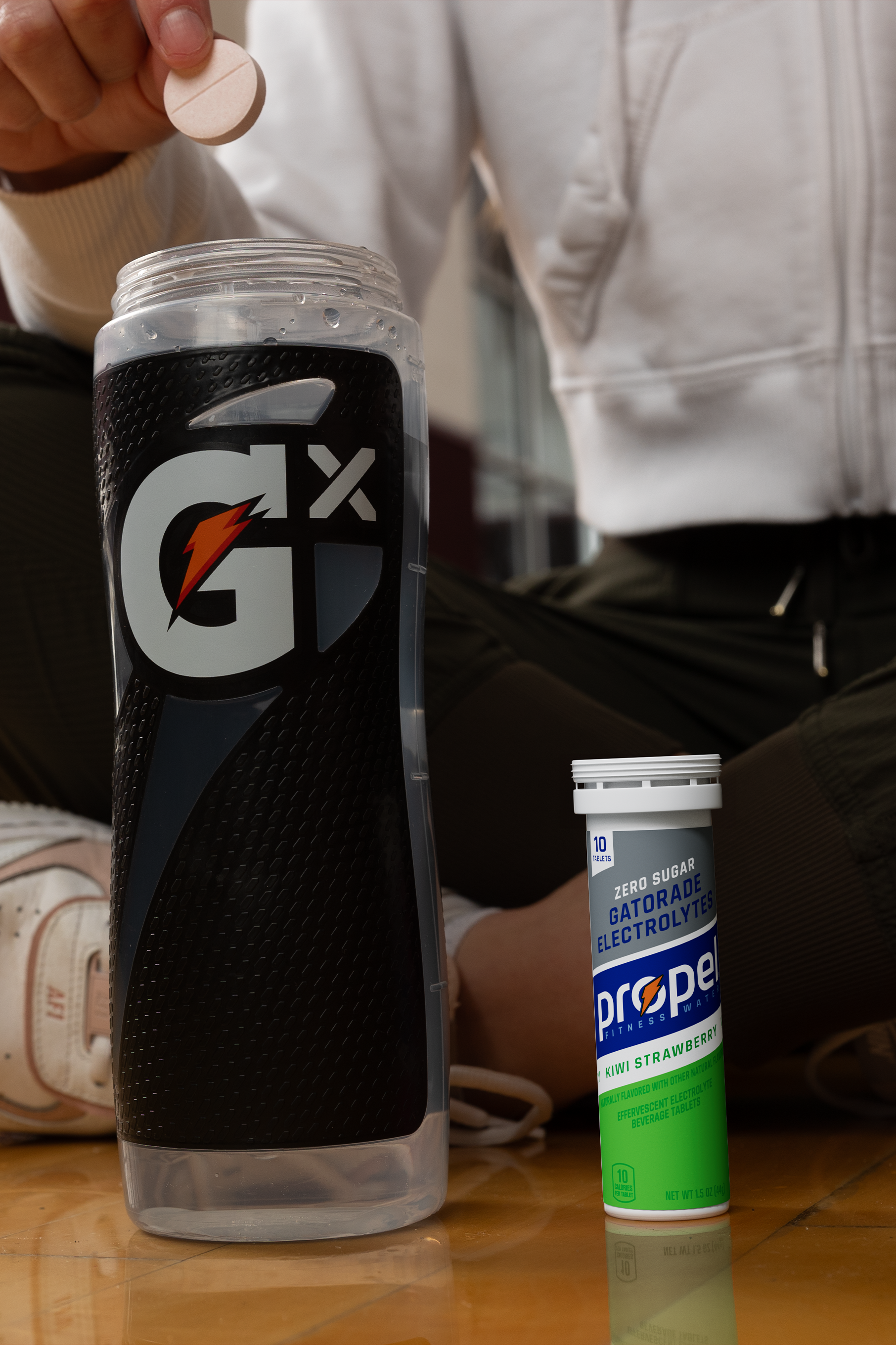 Athlete dropping Propel Kiwi Strawberry Tablet into Gx Squeeze bottle