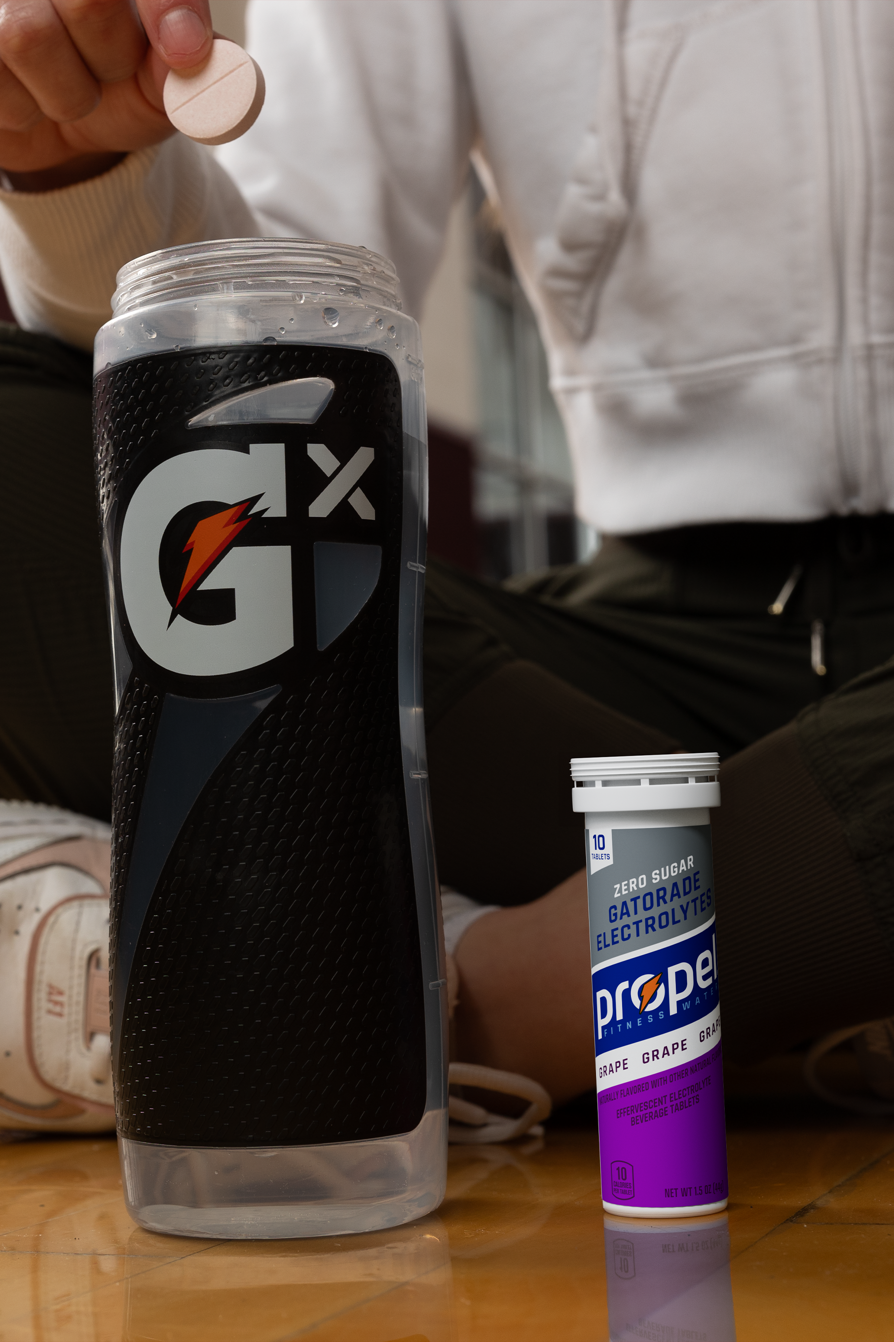 Athlete dropping Propel Grape Tablet into Gx Squeeze bottle