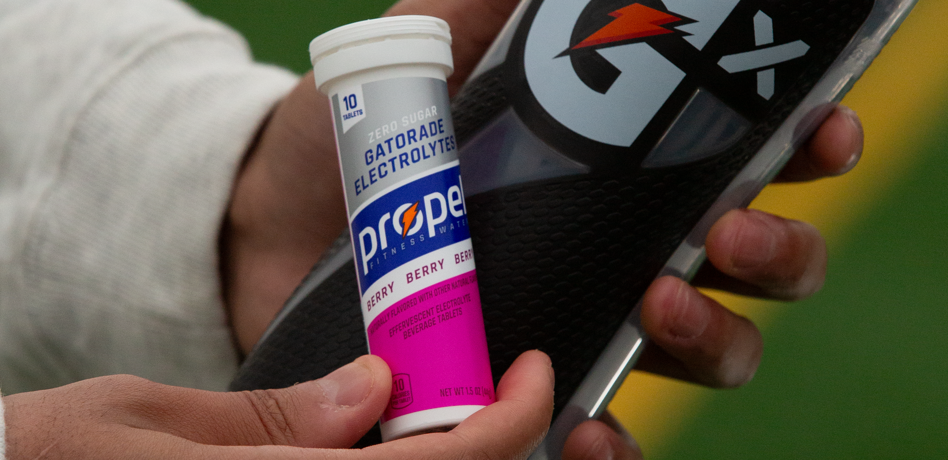 Propel Berry Tablet pack and Gx Squeeze bottle in athlete's hands.