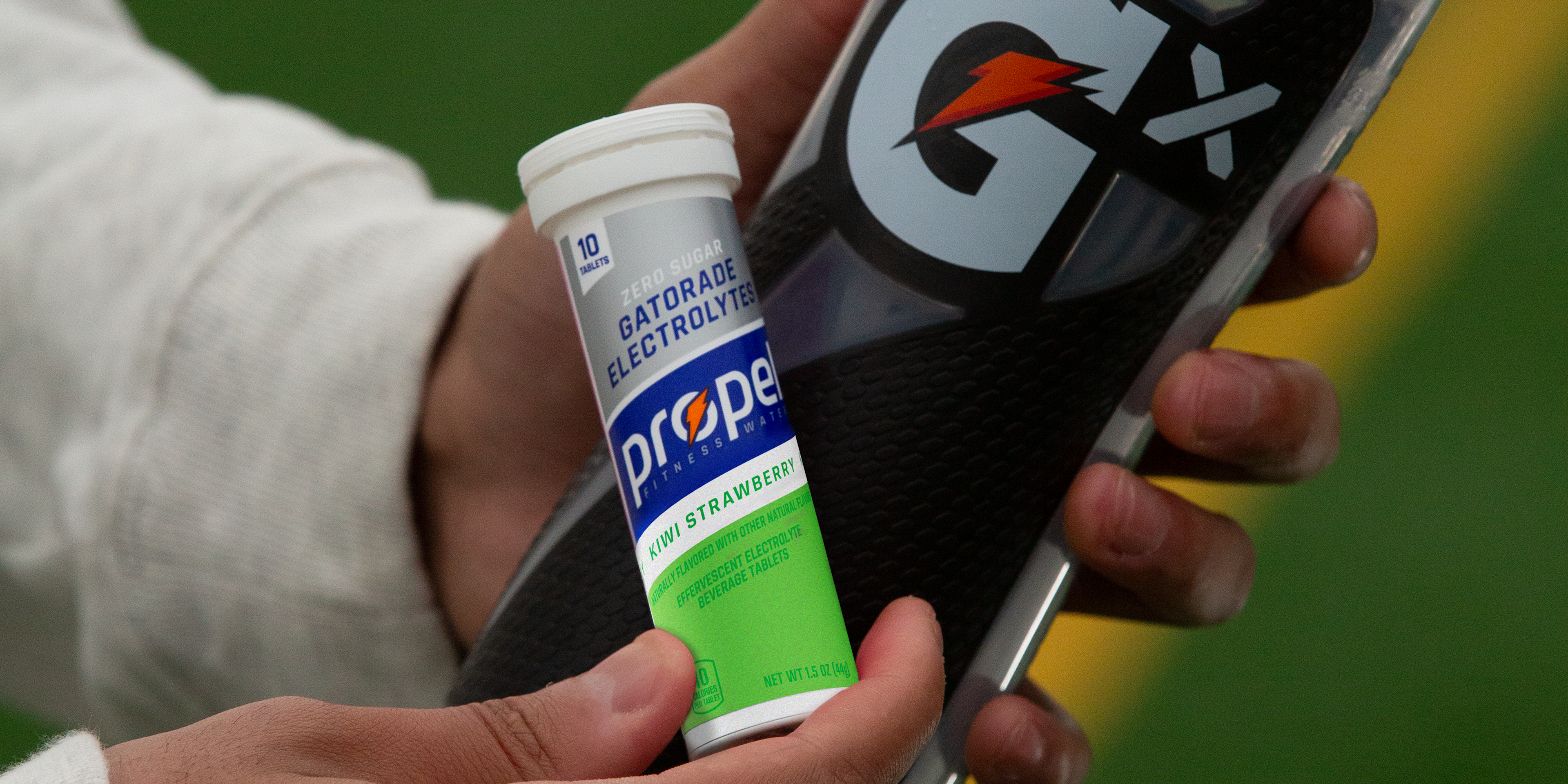 Propel Kiwi Strawberry Tablet pack and Gx Squeeze bottle in athlete's hands.