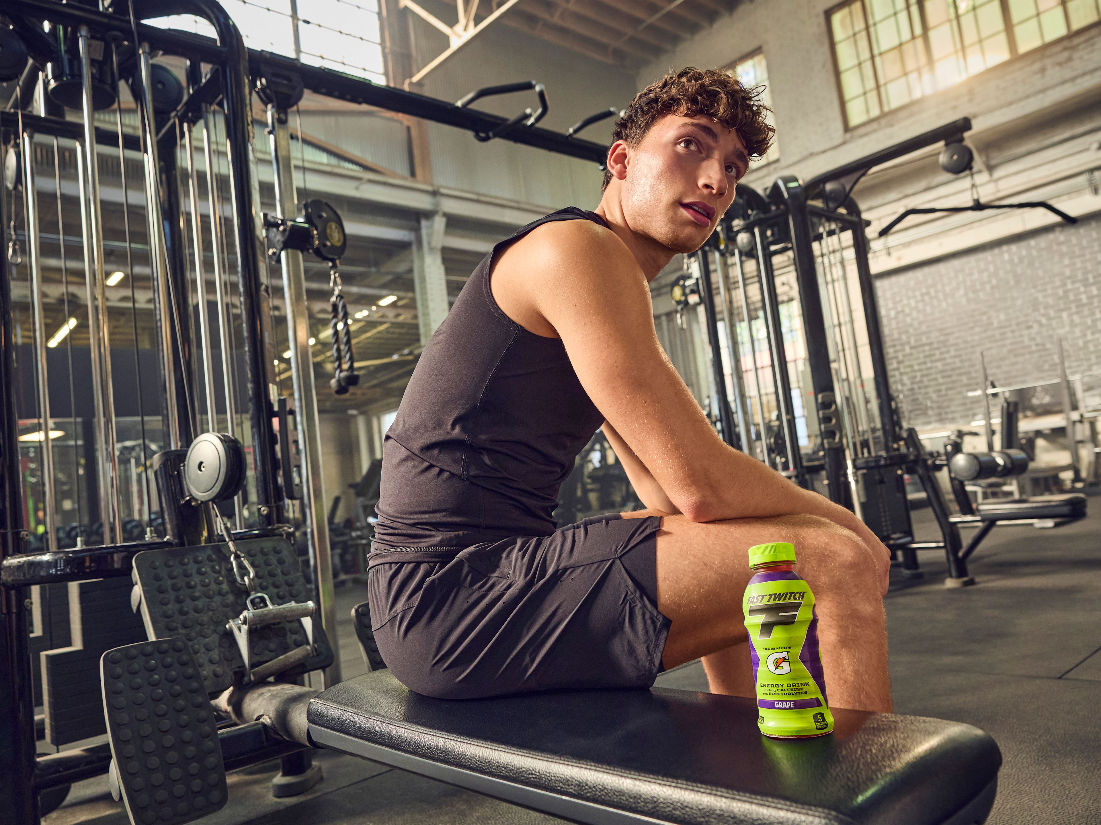 Athlete in the gym with a Fast Twitch ready to drink Grape bottle.