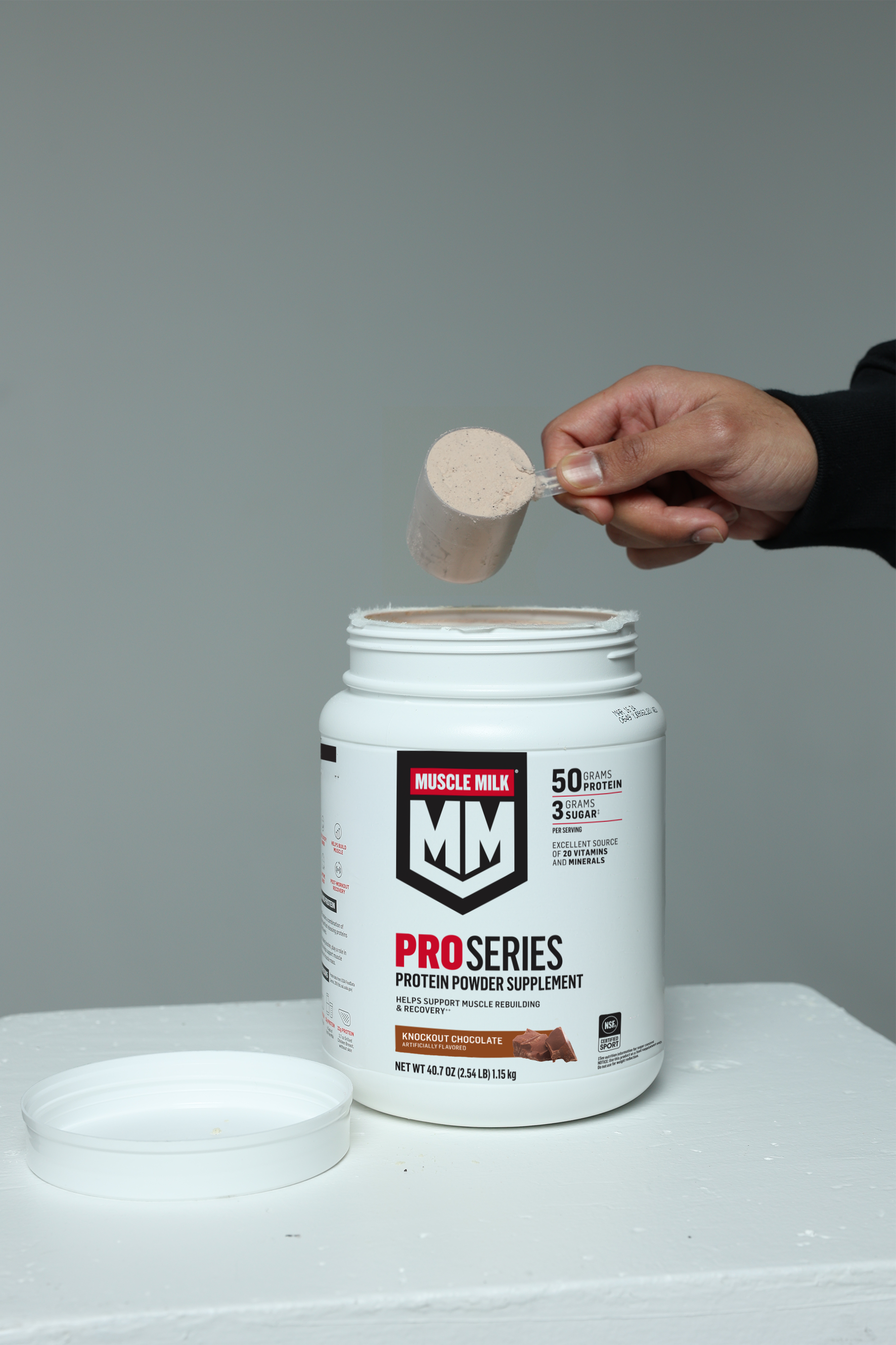Muscle Milk Pro Series Knockout Chocolate protein powder being scooped out of canister