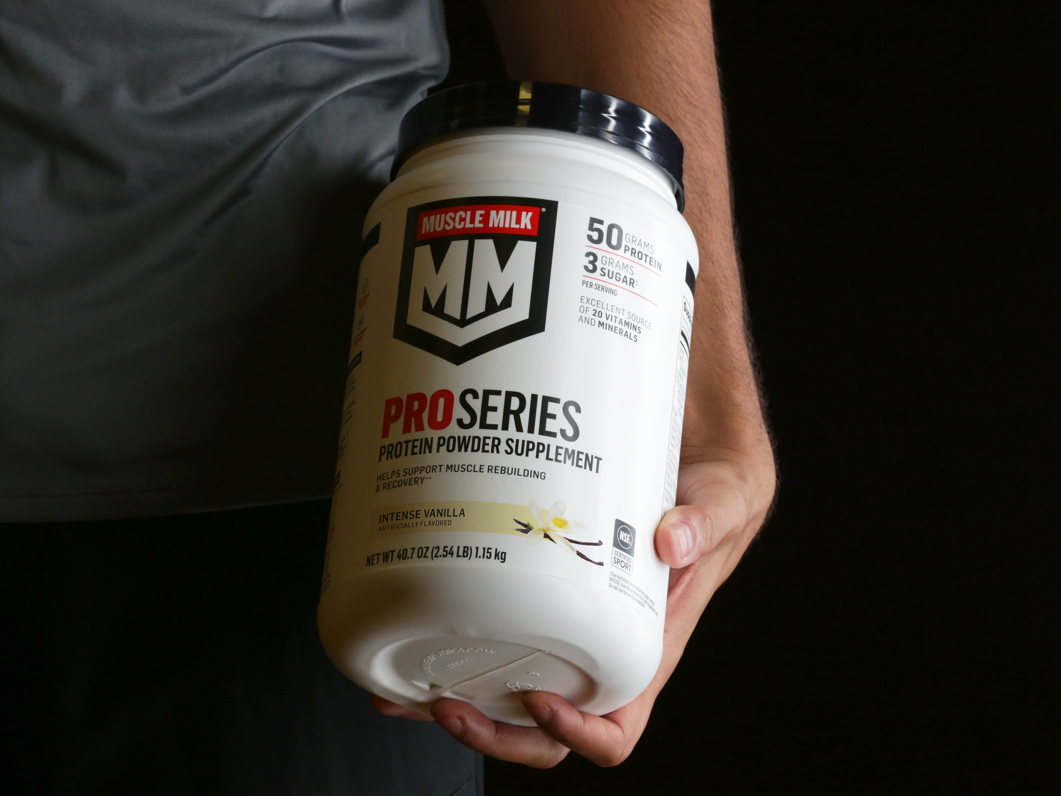 Athlete holding Muscle Milk Pro Series Intense Vanilla Protein Powder canister