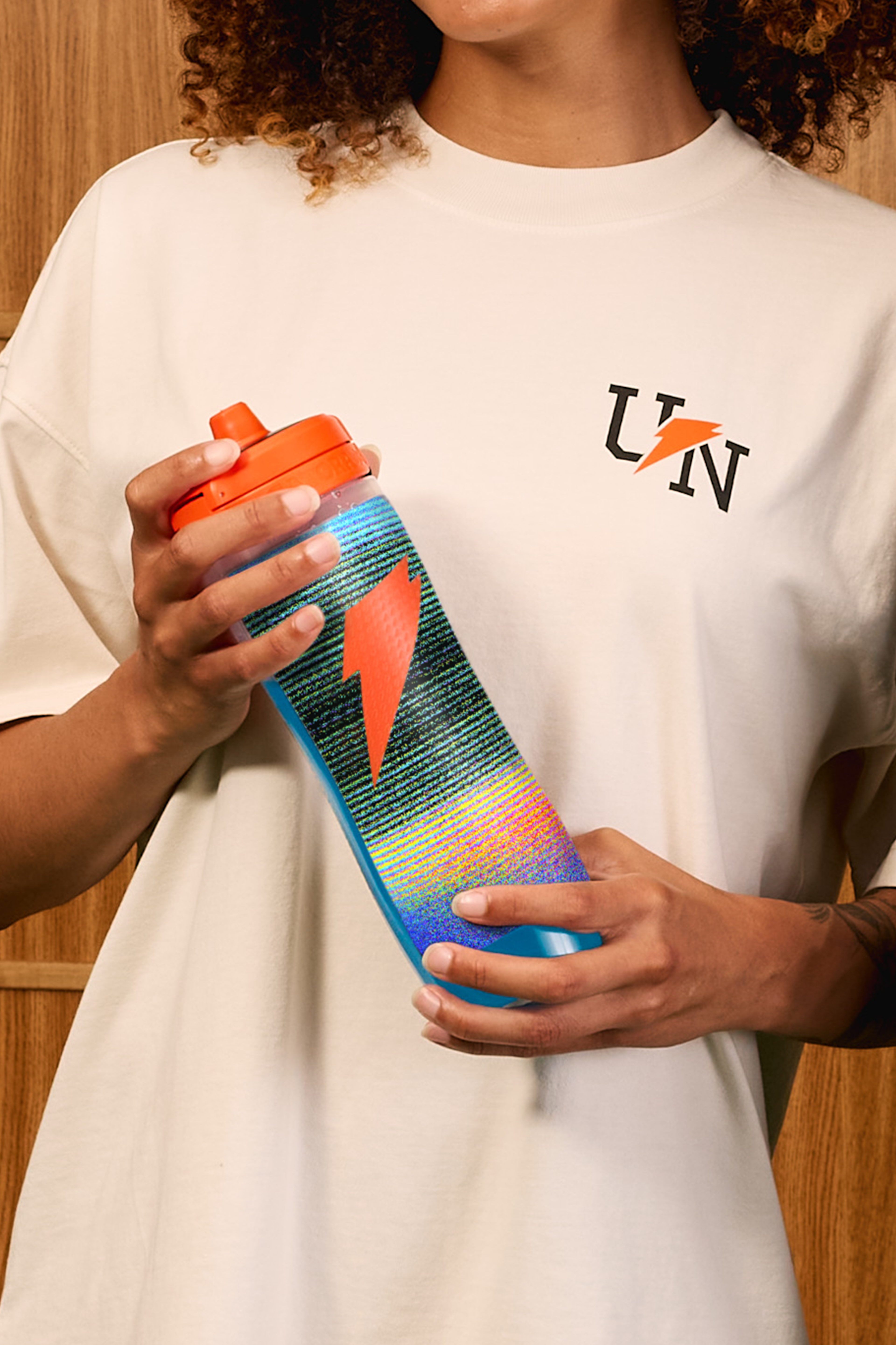 Woman wearing the Gatorade x UNINTERRUPTED T-Shirt and holding a Gatorade x UNINTERRUPTED Bottle