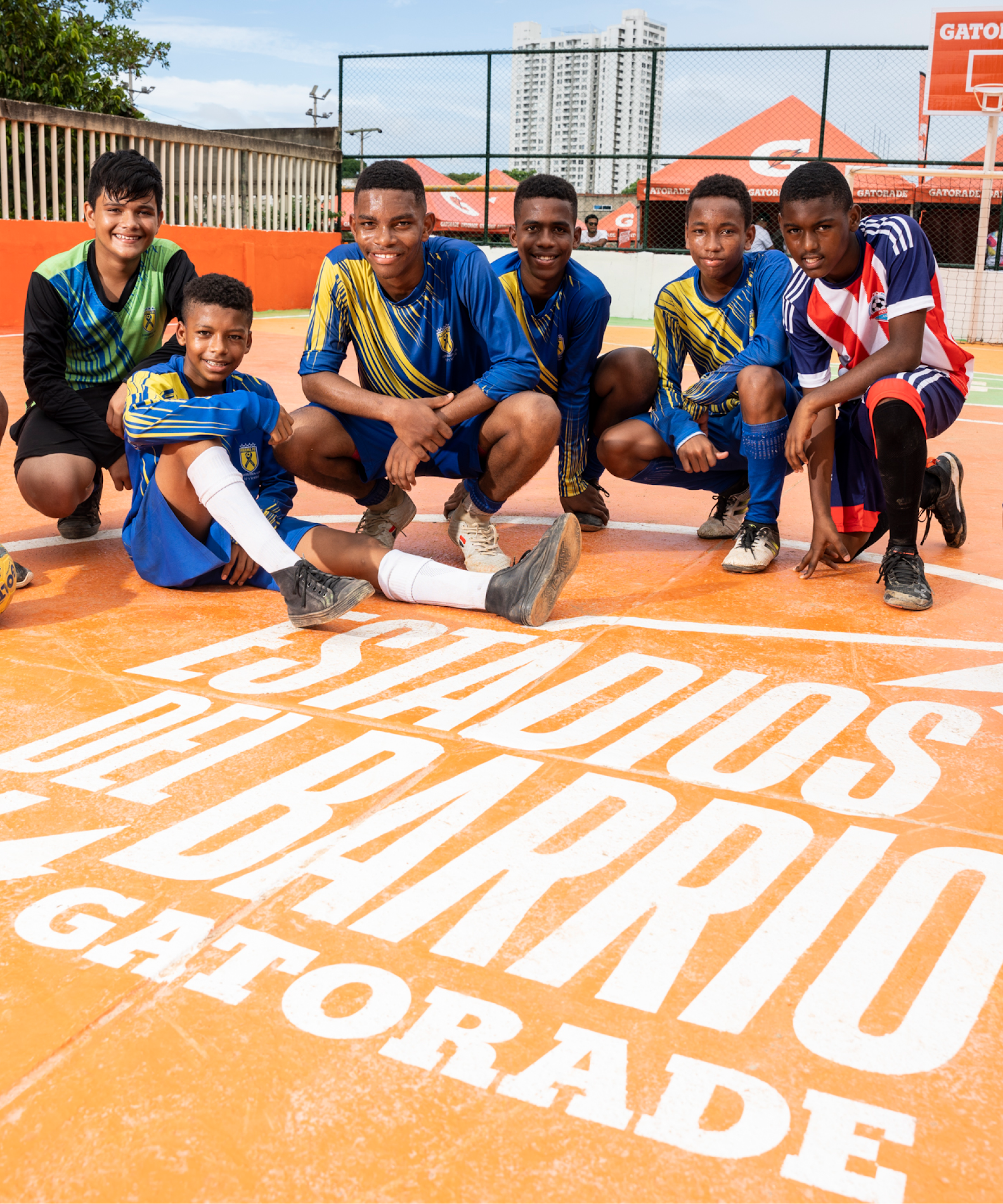 Men on a sports court sitting in front of the words written into the court "Estadios del barrio - Gatorade"