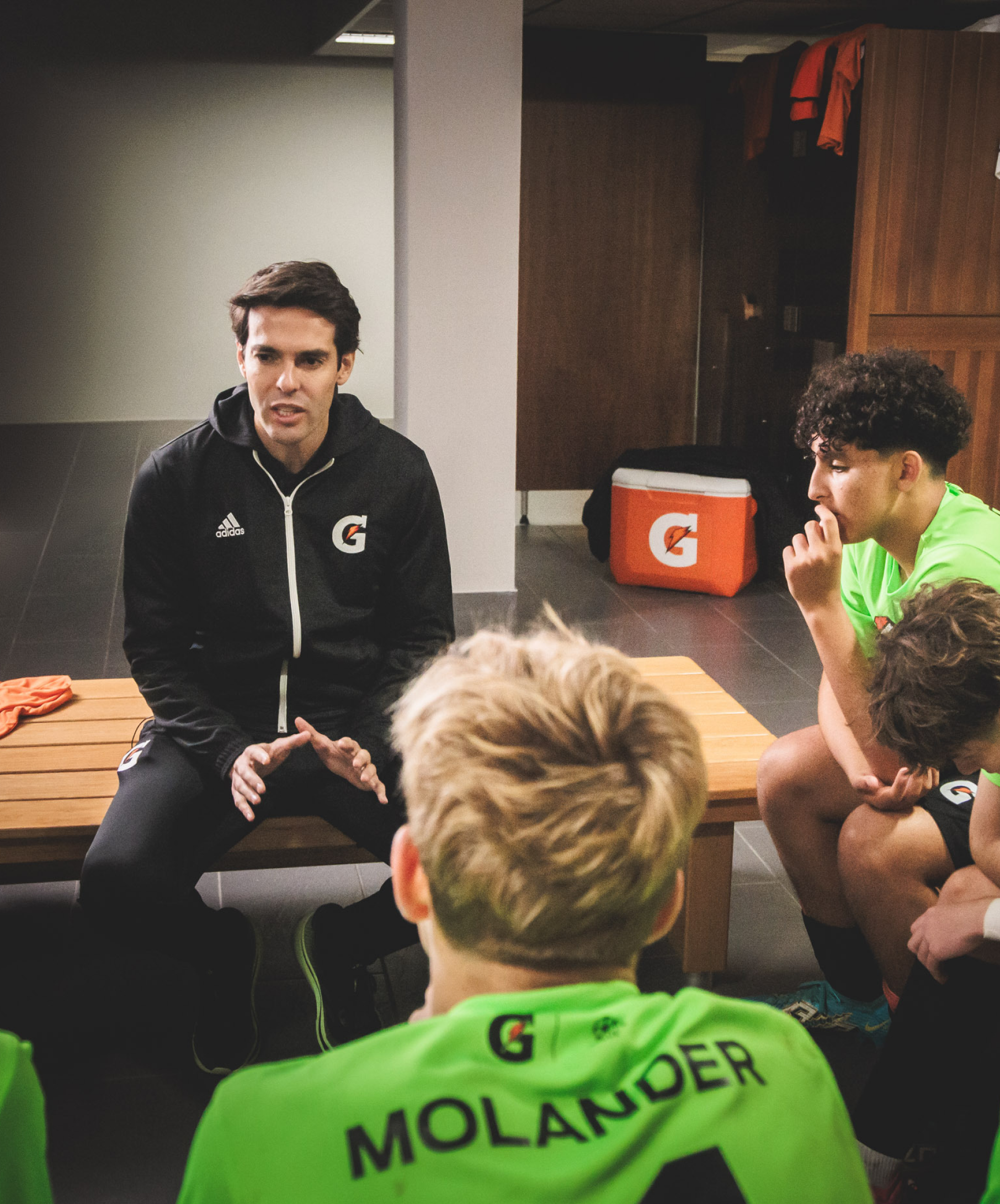 Coach sitting with a group of boys in soccer jerseys, speaking with them