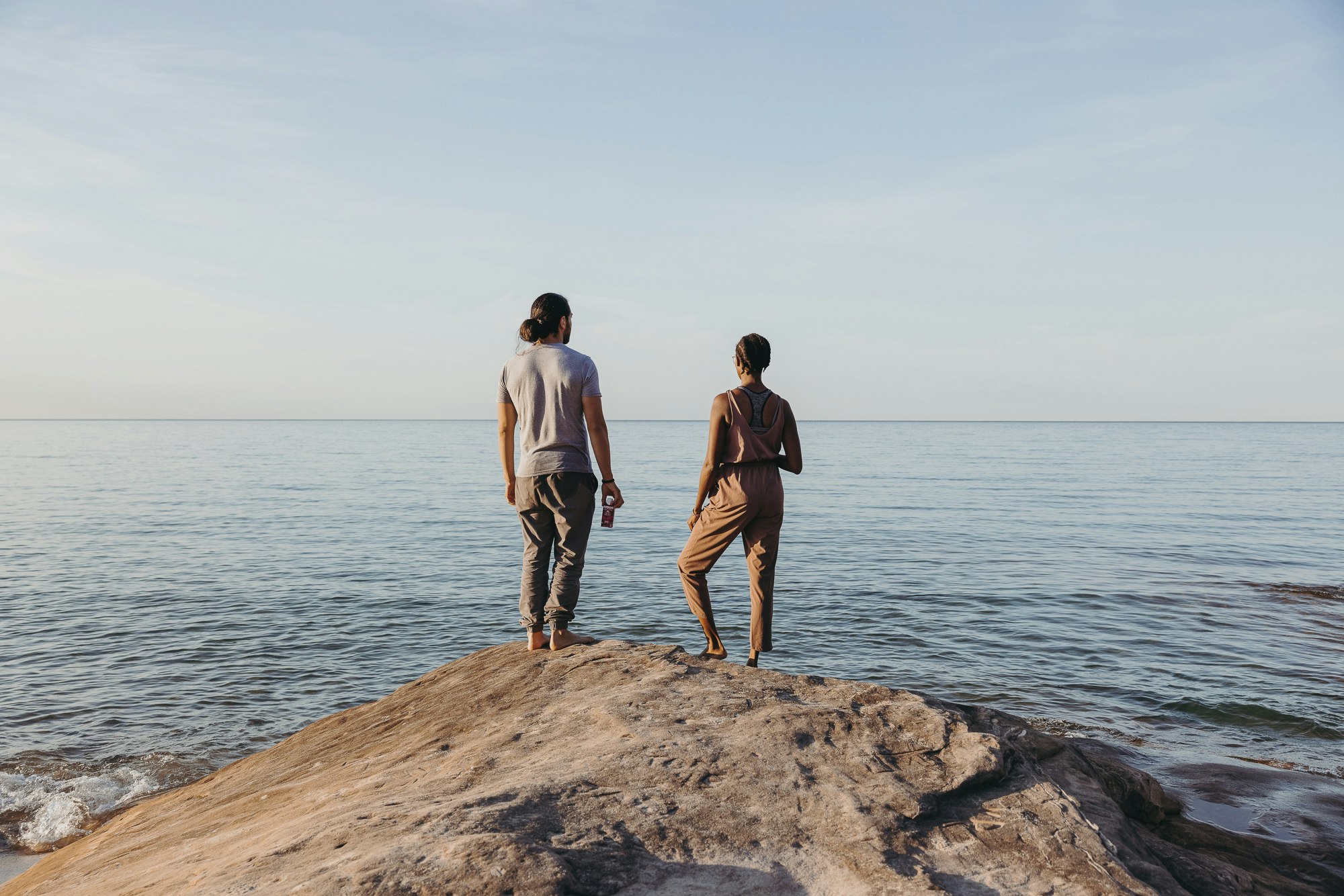 man and woman on cliff overlooking ocean