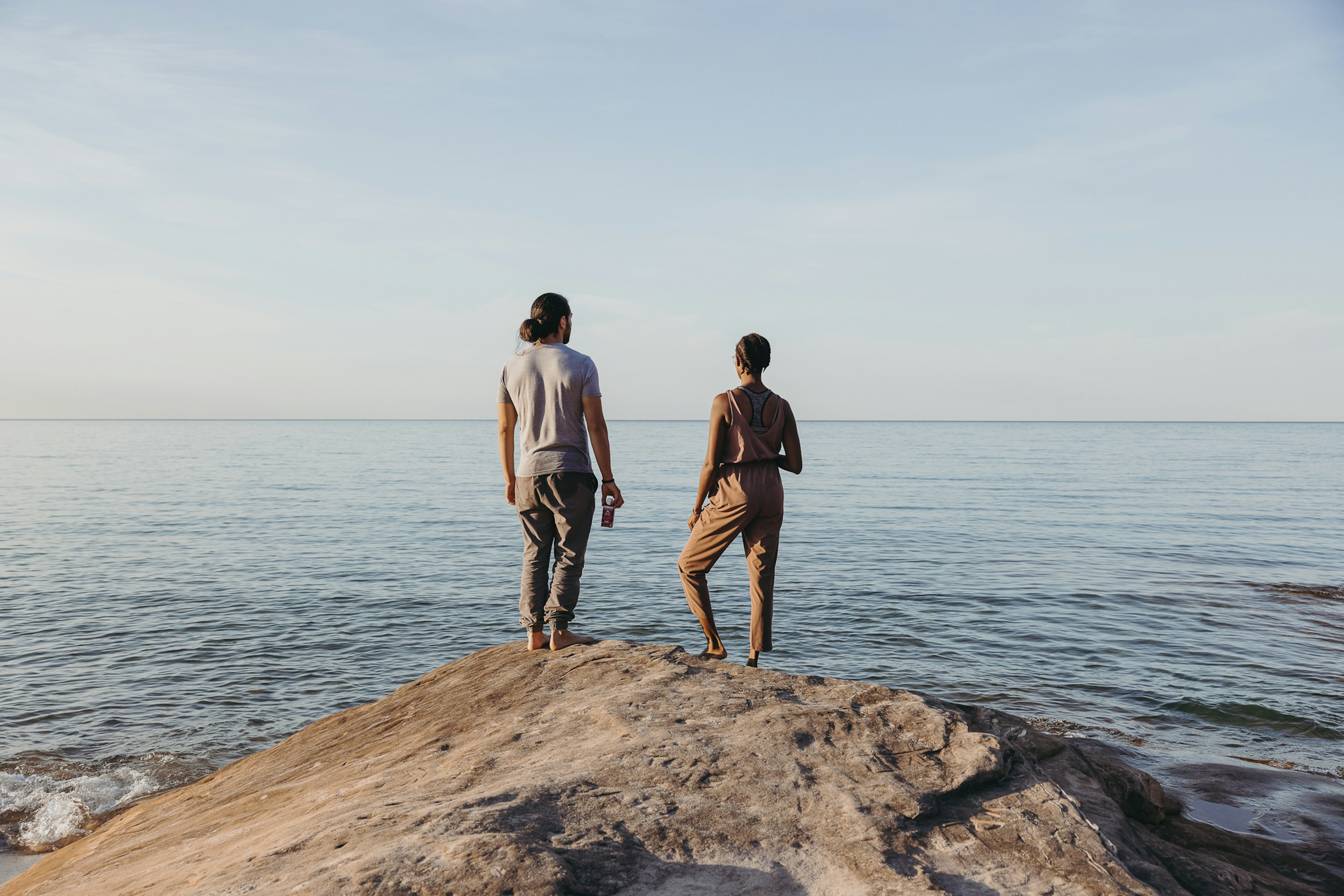 man and woman on cliff overlooking ocean