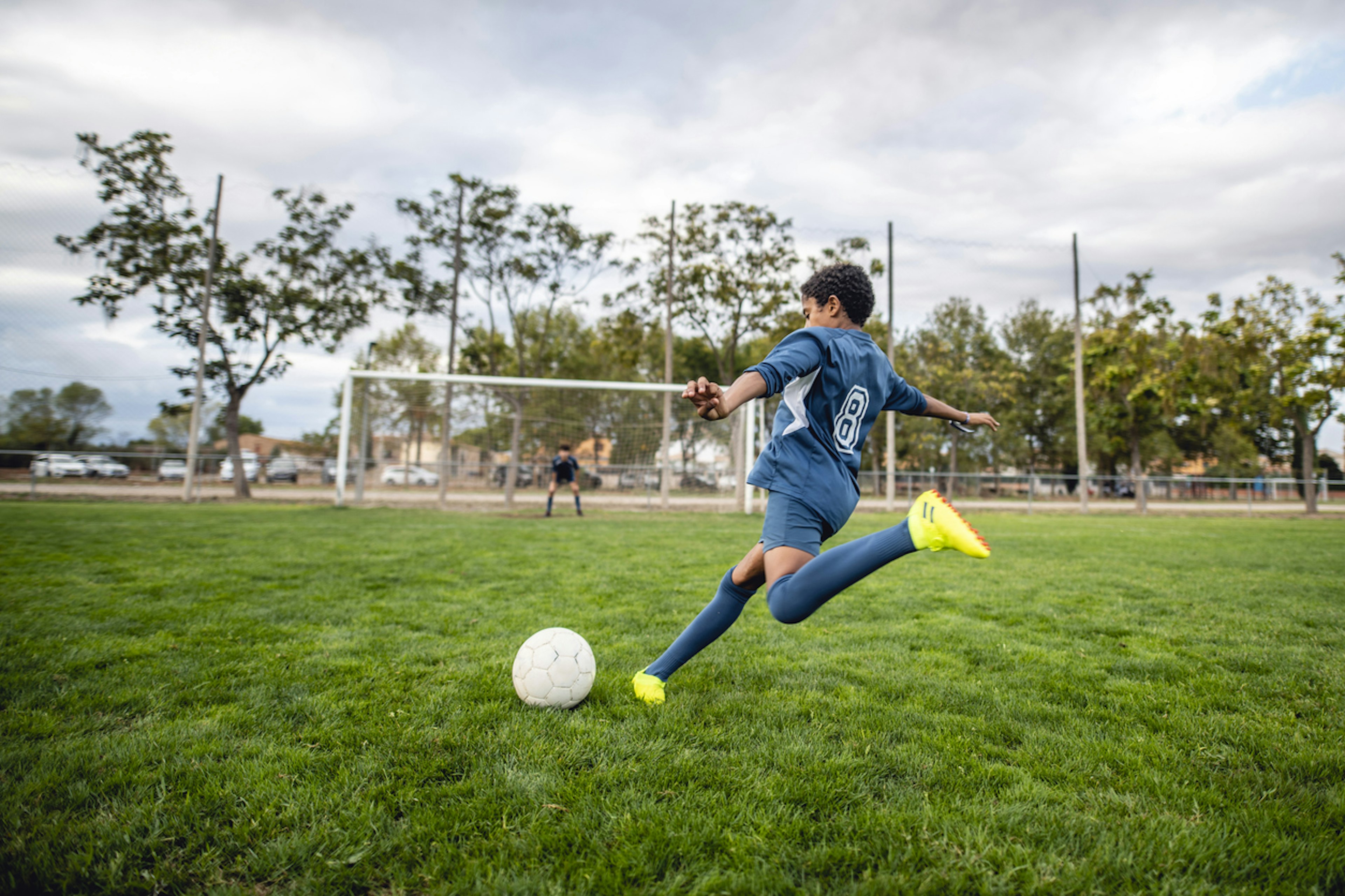 boy kicking soccer ball towards goal