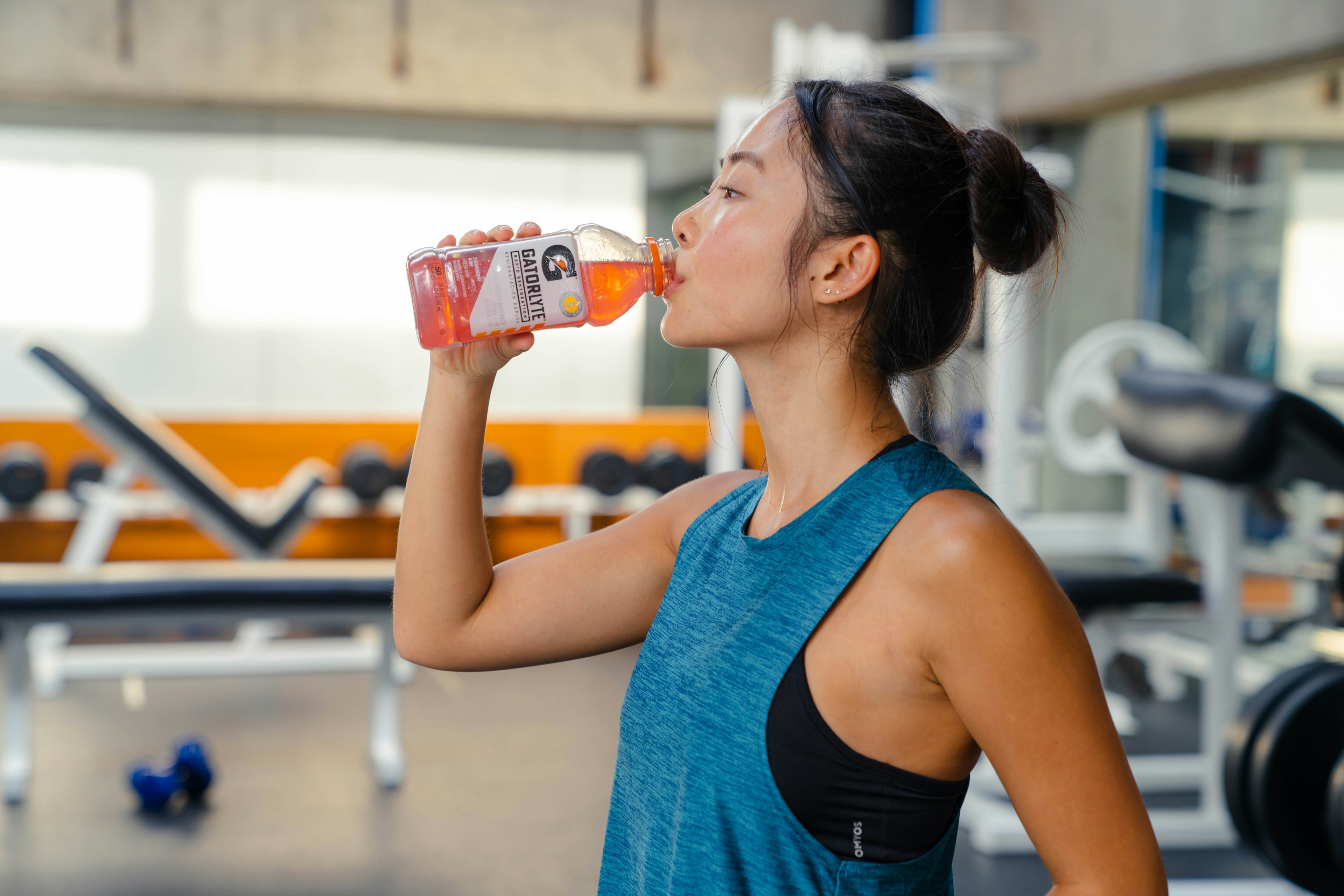 woman drinking gatorade in a gym