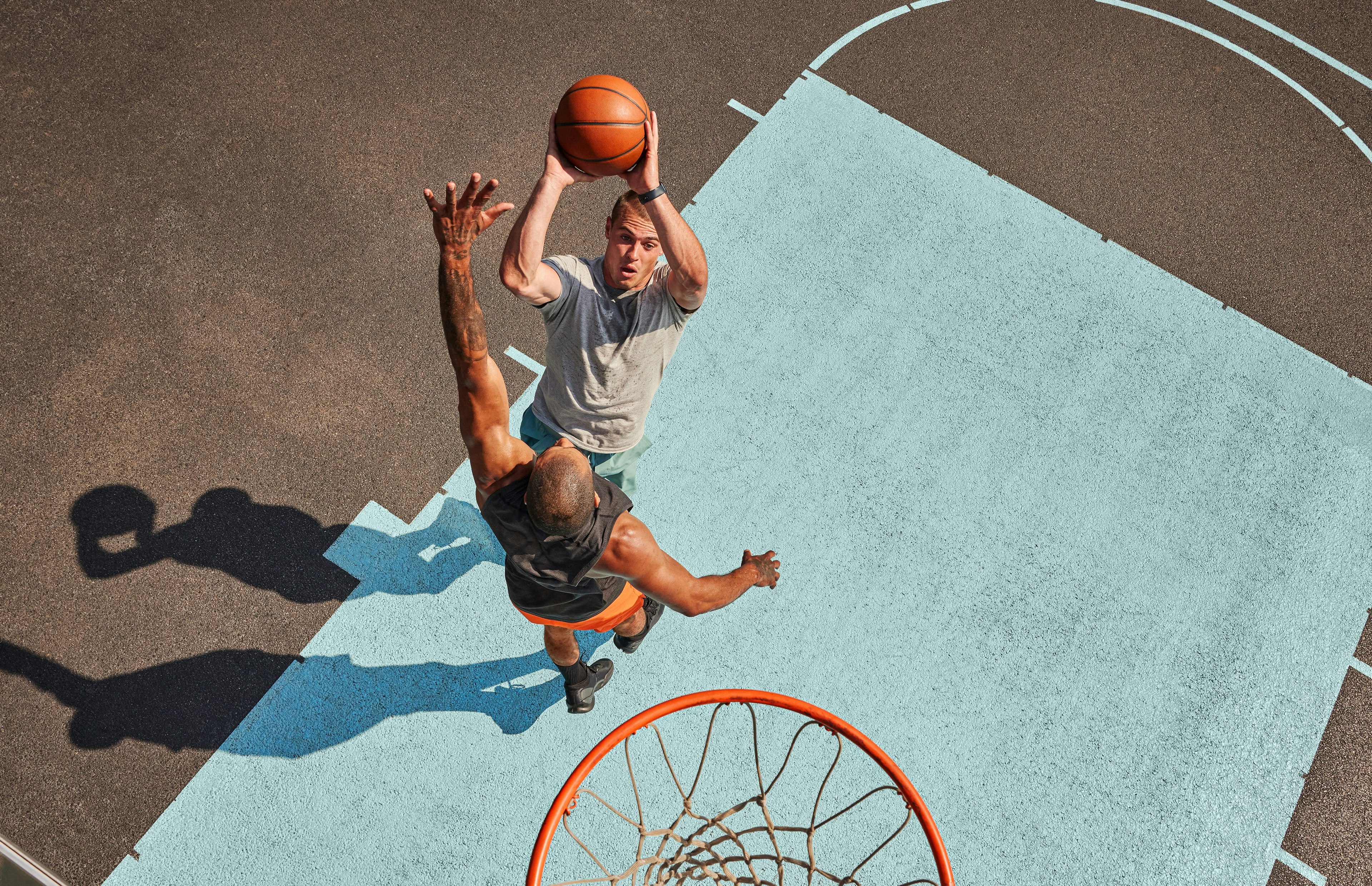 man shooting basketball over another man