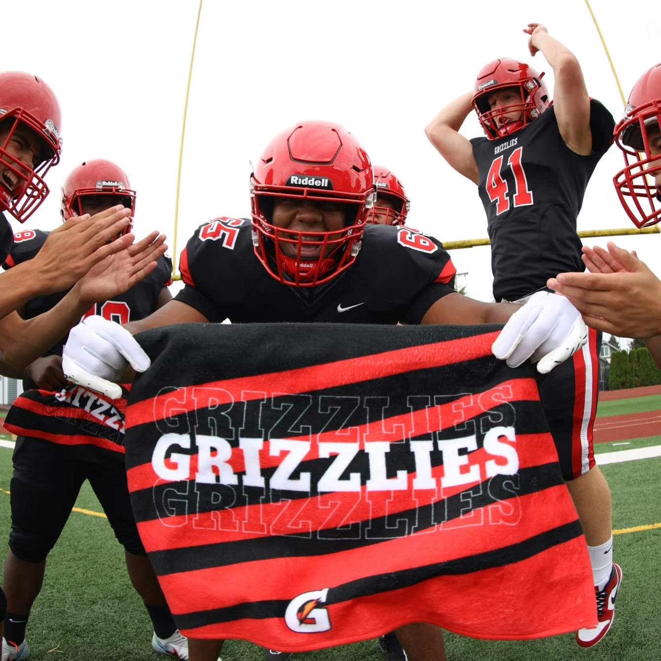 football team on the field holding up a customized towel that says grizzlies