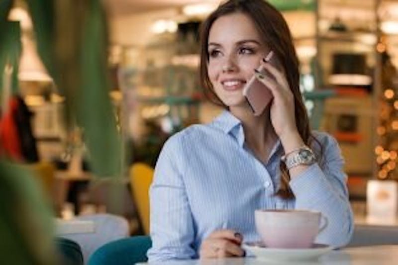woman on her cell phone with a coffee mug in front of her