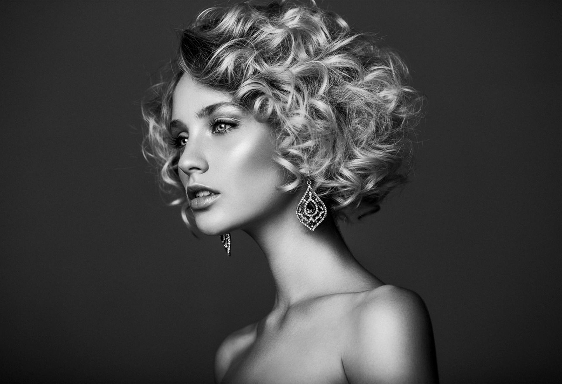 Black and white image of a glamorous woman with short curly hair and big earrings