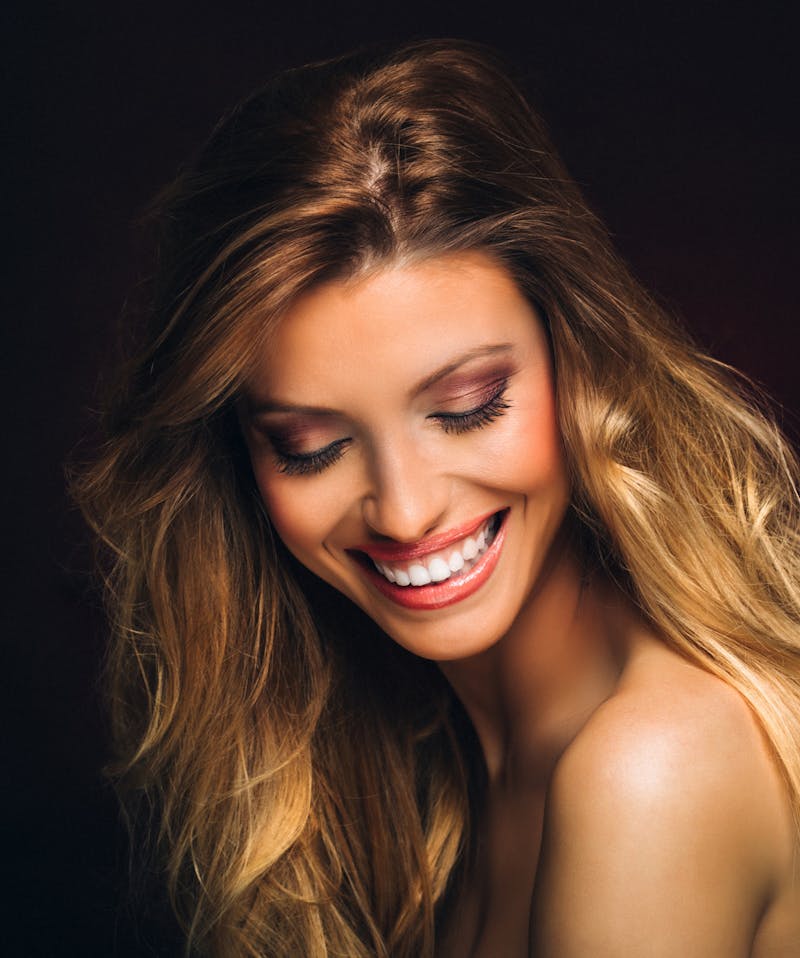 Woman with long medium blonde hair smiling while looking down