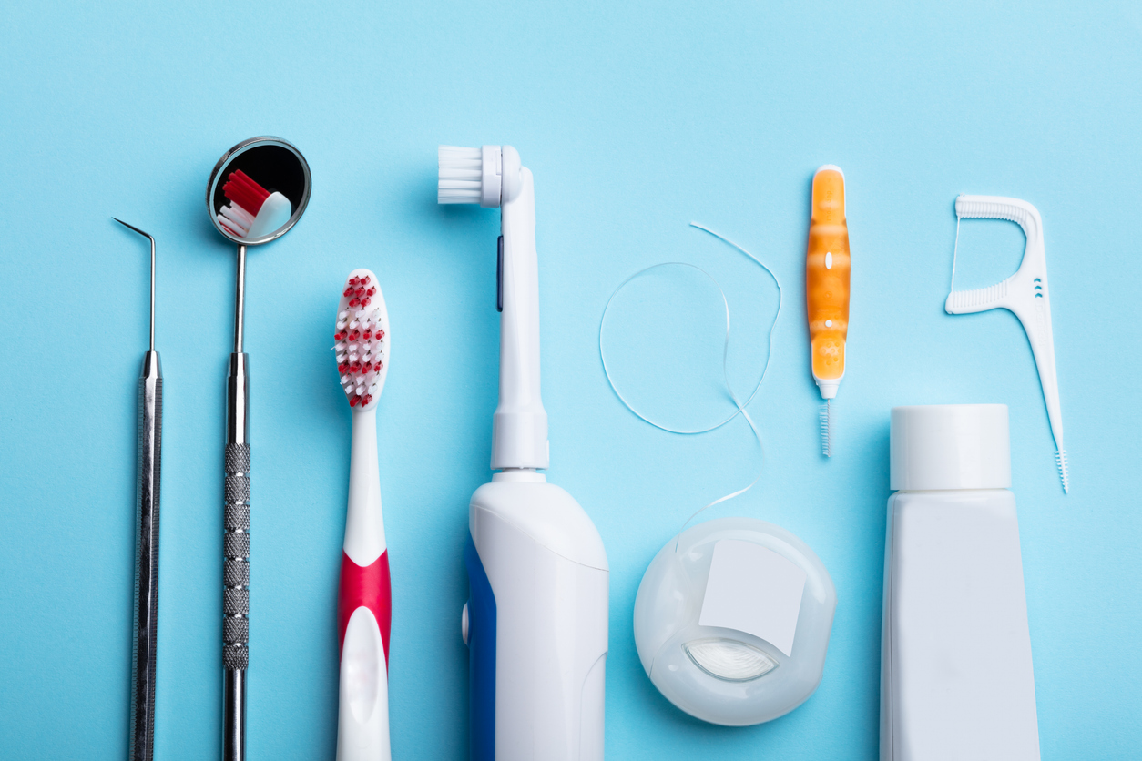 Dental hygiene tools including toothbrushes, floss, and dental instruments arranged on a blue background.