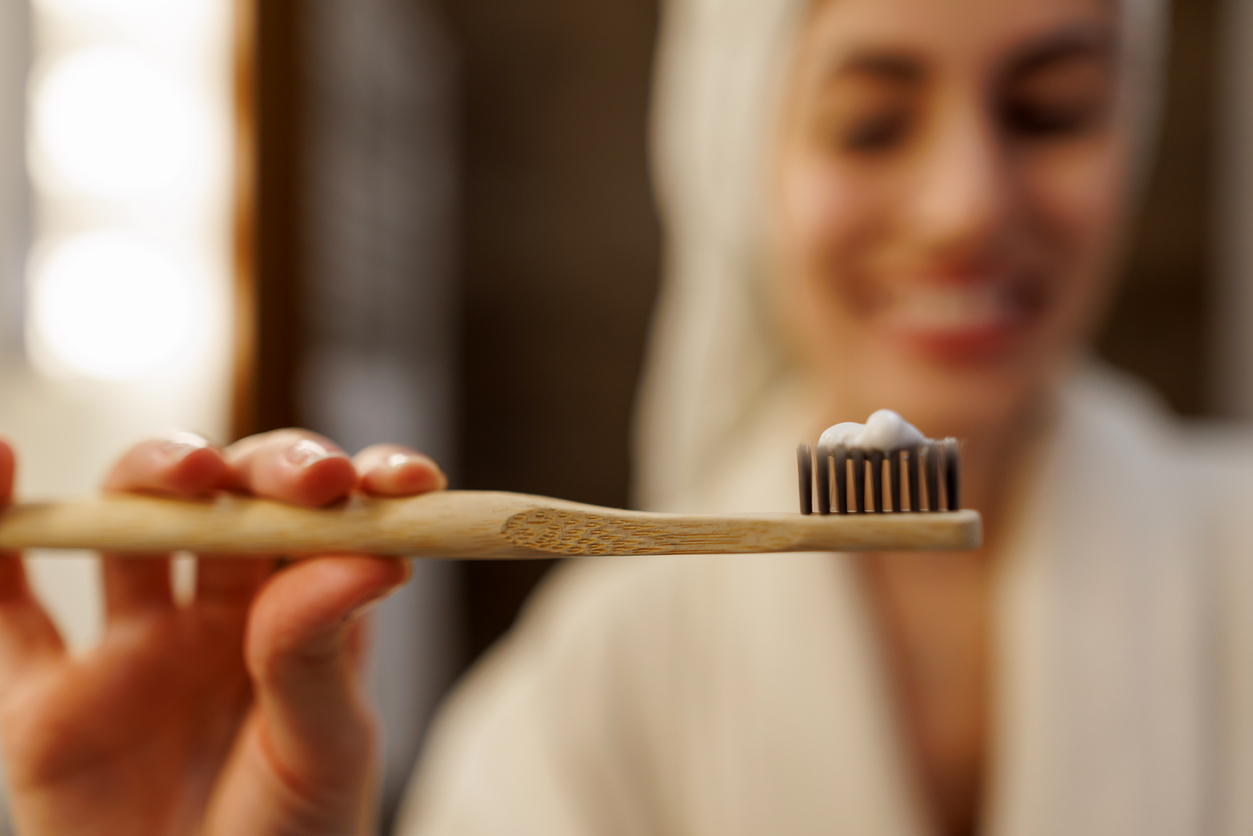 Woman holding a bamboo toothbrush with toothpaste before brushing her teeth
