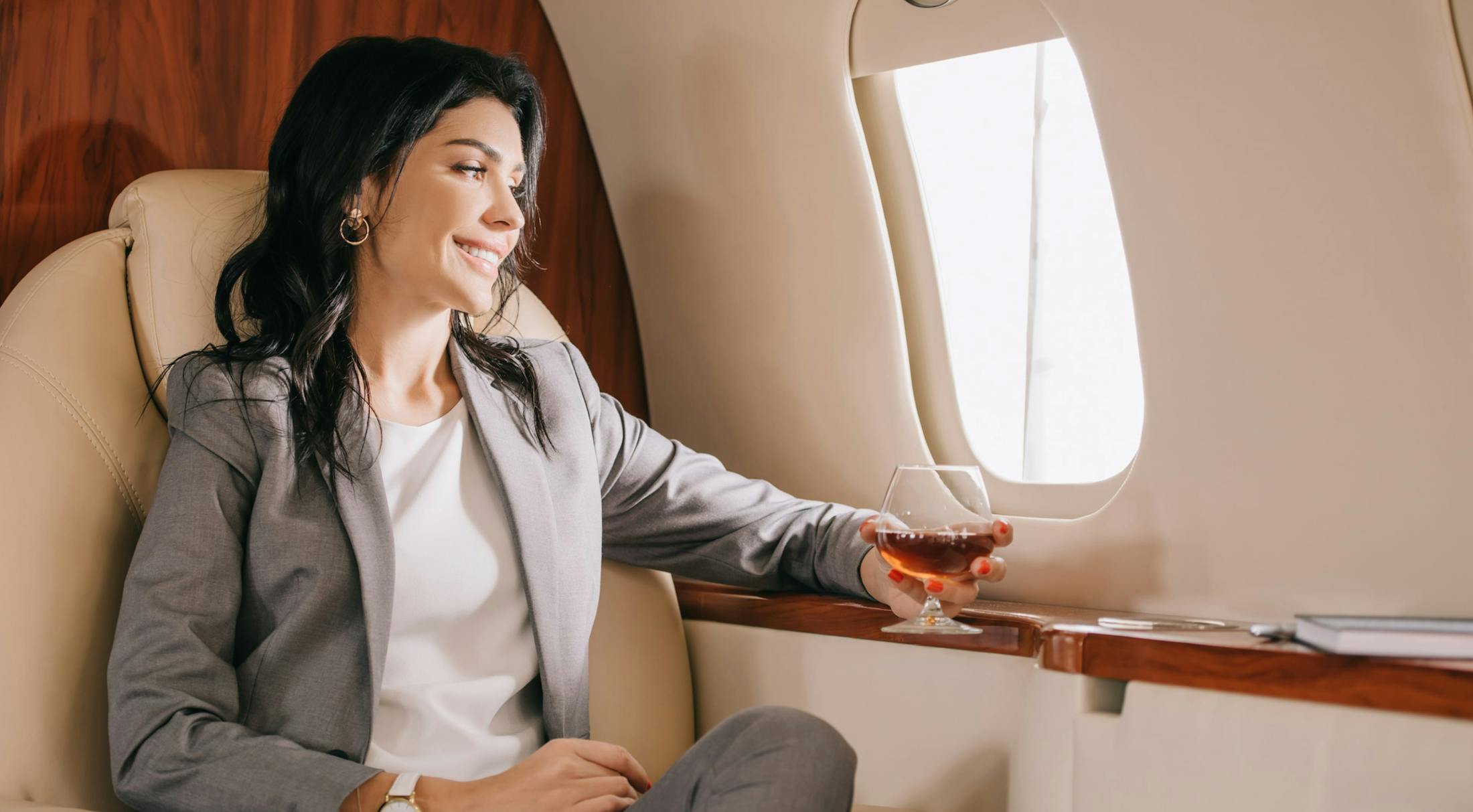 Woman drinking wine and looking out of plane window