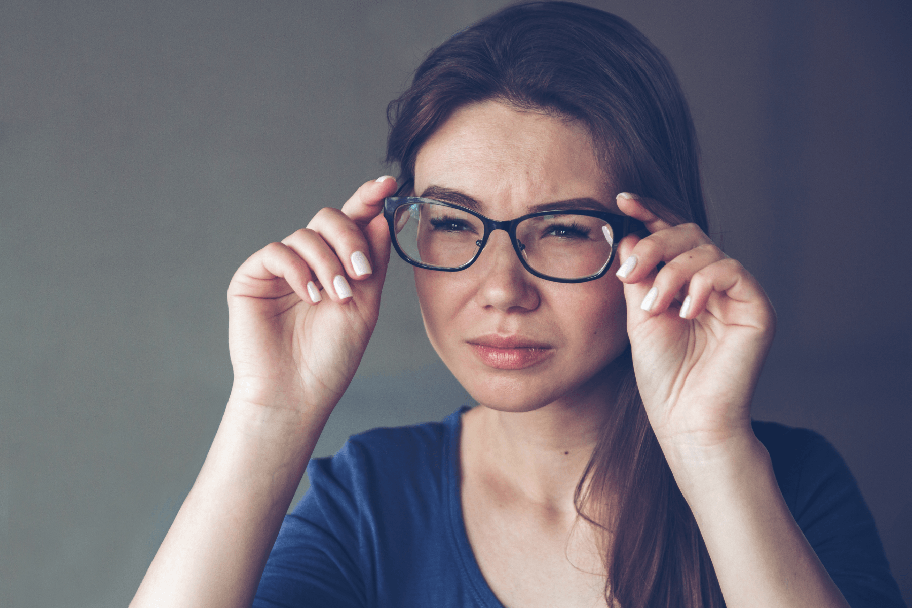 Woman squinting and looking through glasses