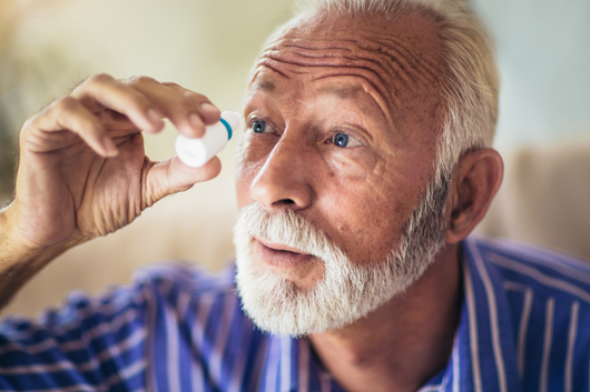 man using eye drops