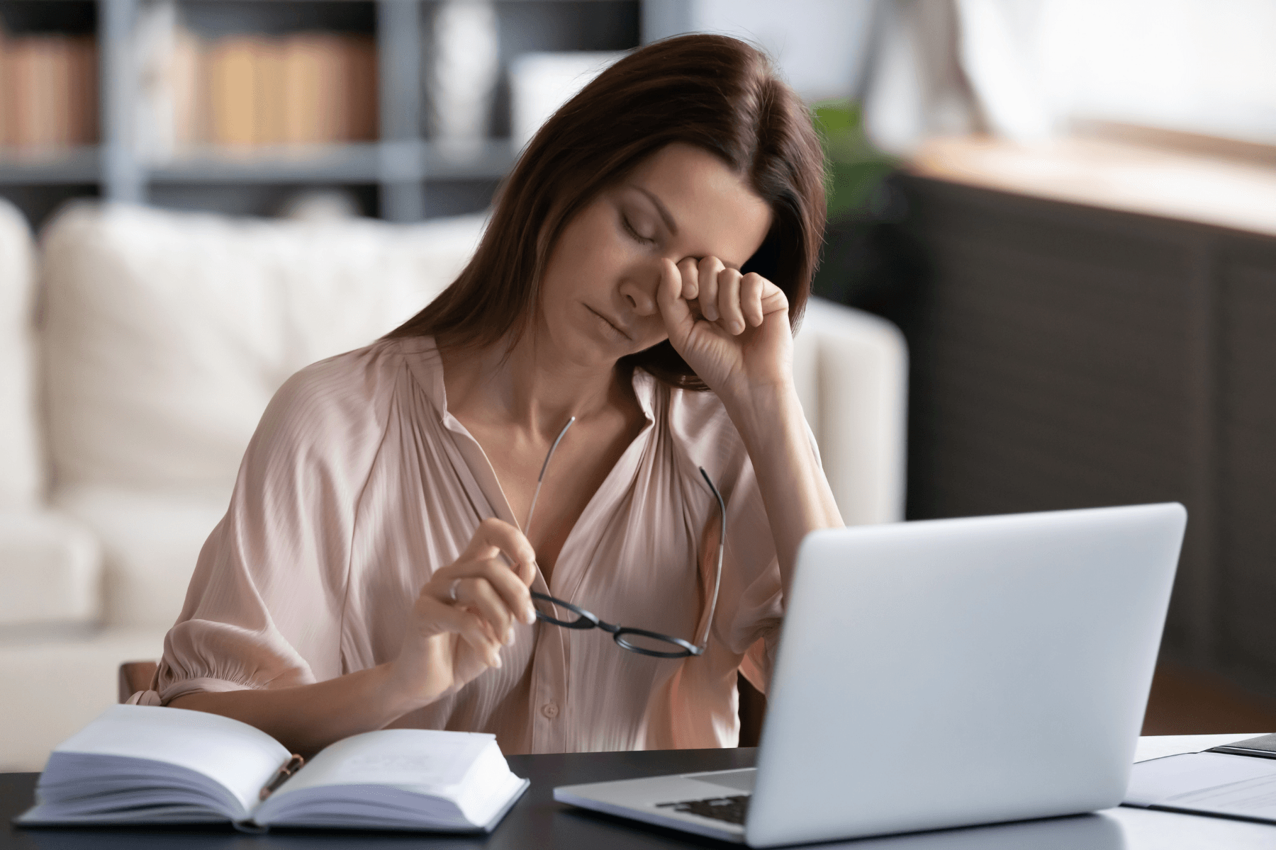 Tired woman rubbing eyes and holding glasses