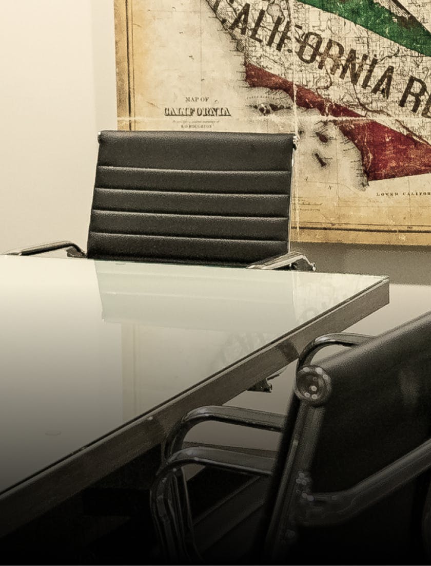 a glass table with a black chair and a map on the wall of southern Calirornia