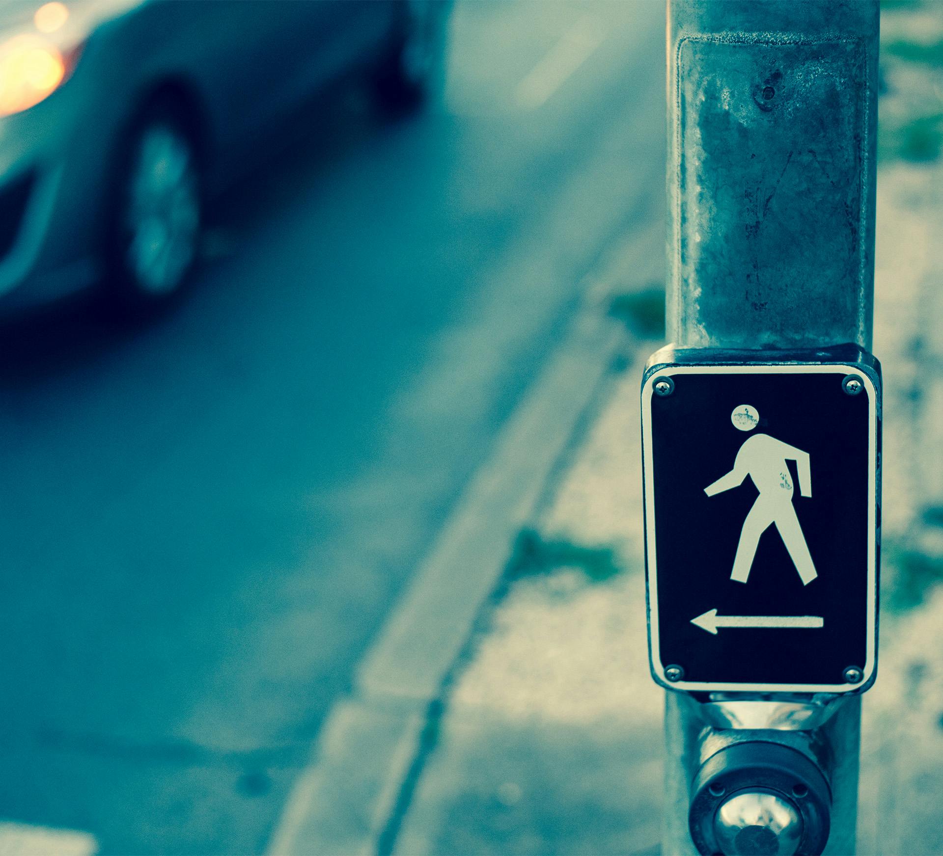 Crosswalk sign on a pole with a vehicle in the background