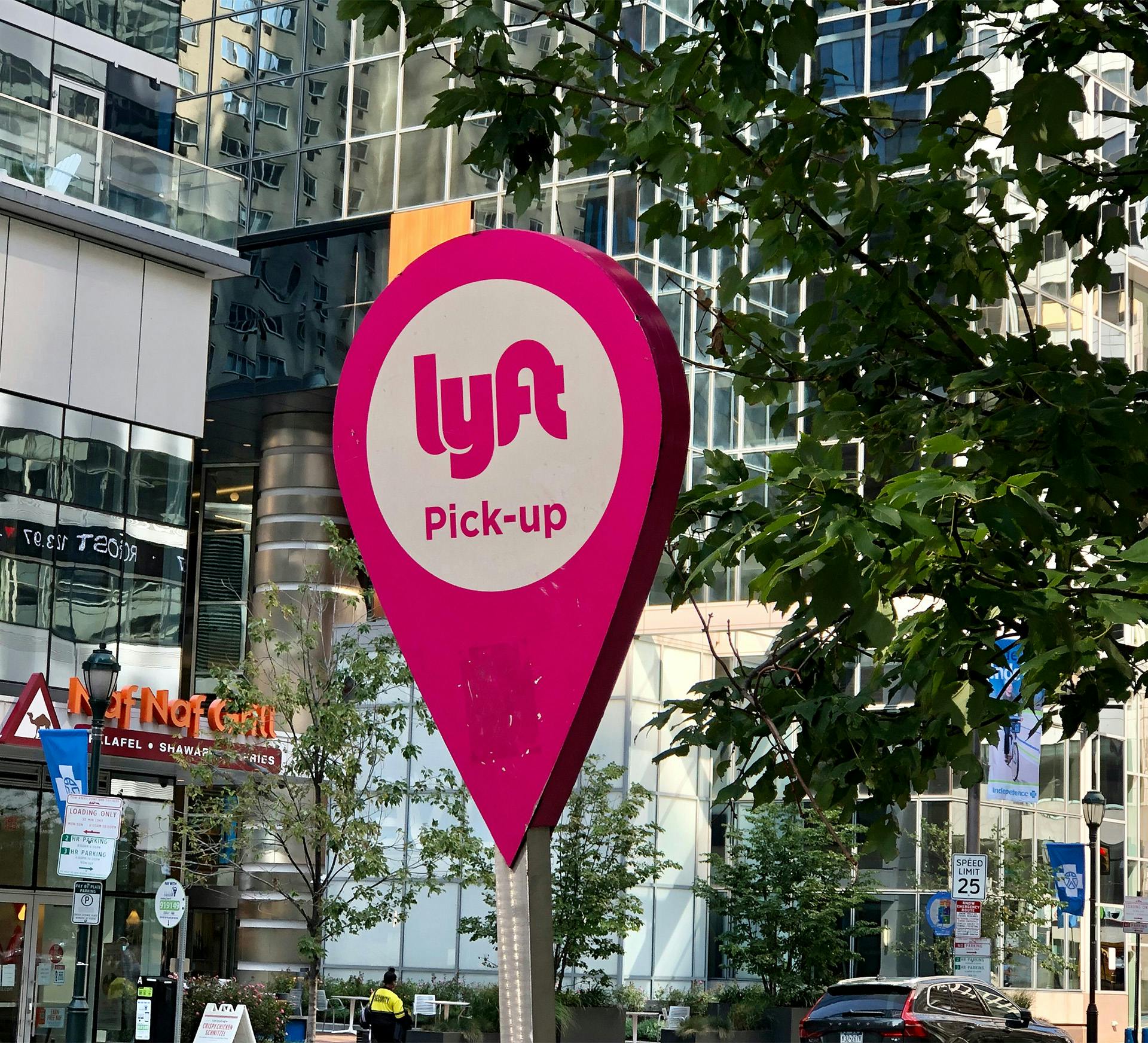 Lyft sign on a pole in a city with a building in the background