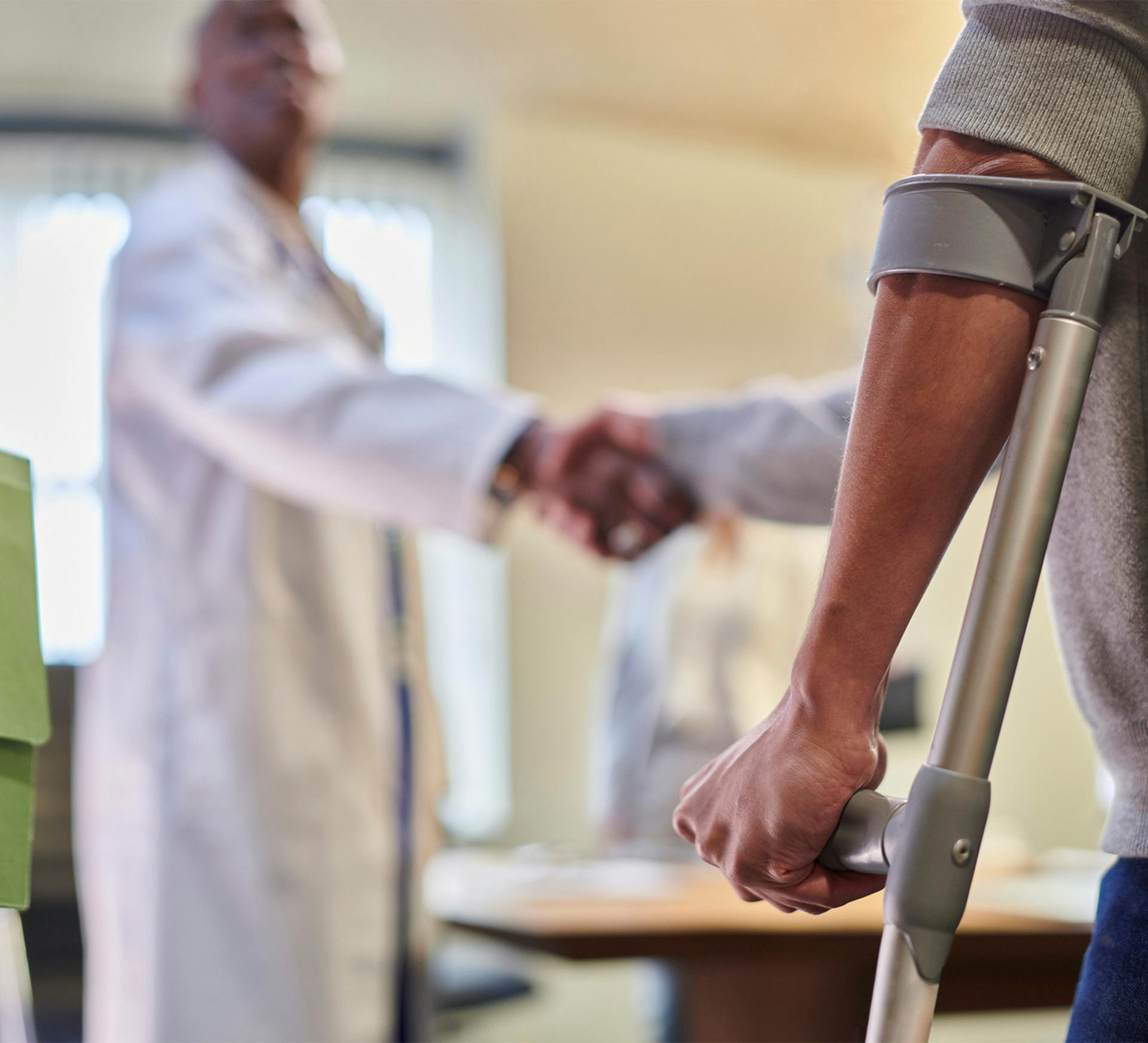 a man in crutches shaking the hand of a doctor in a doctor's office