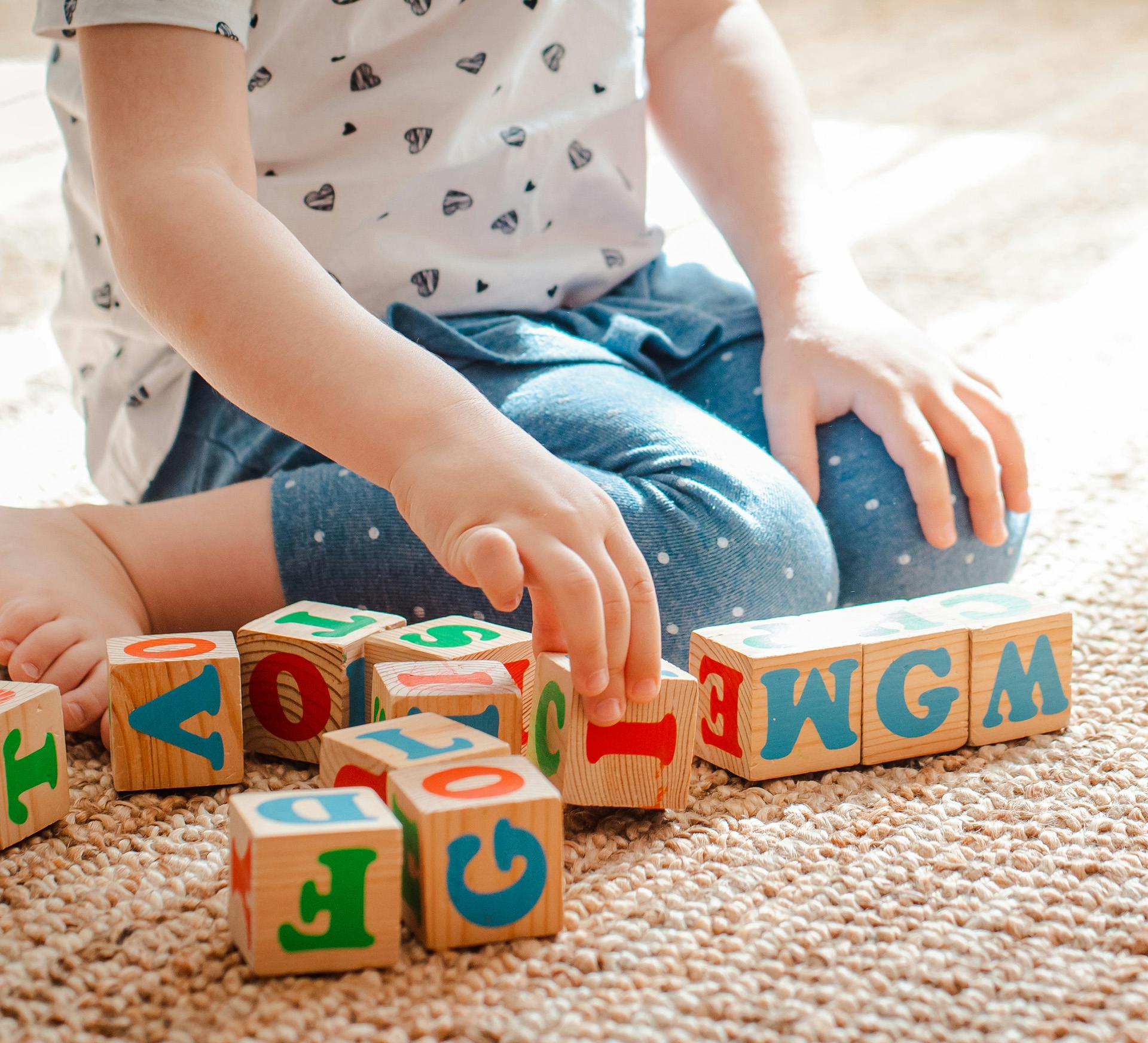 a child playing with wooden blocks on the floor