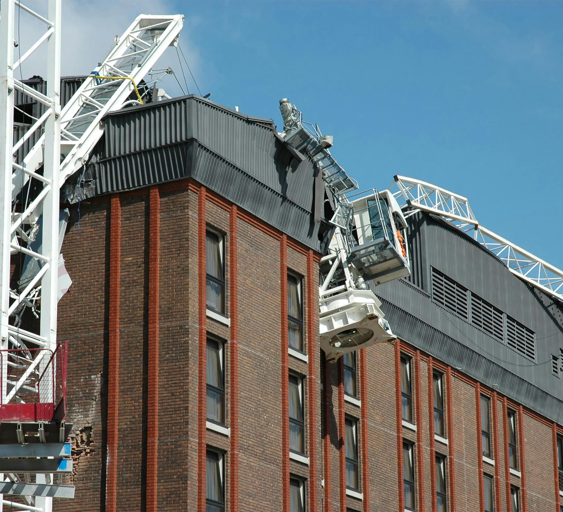 picture of a crane accident on top of a now damaged buidling