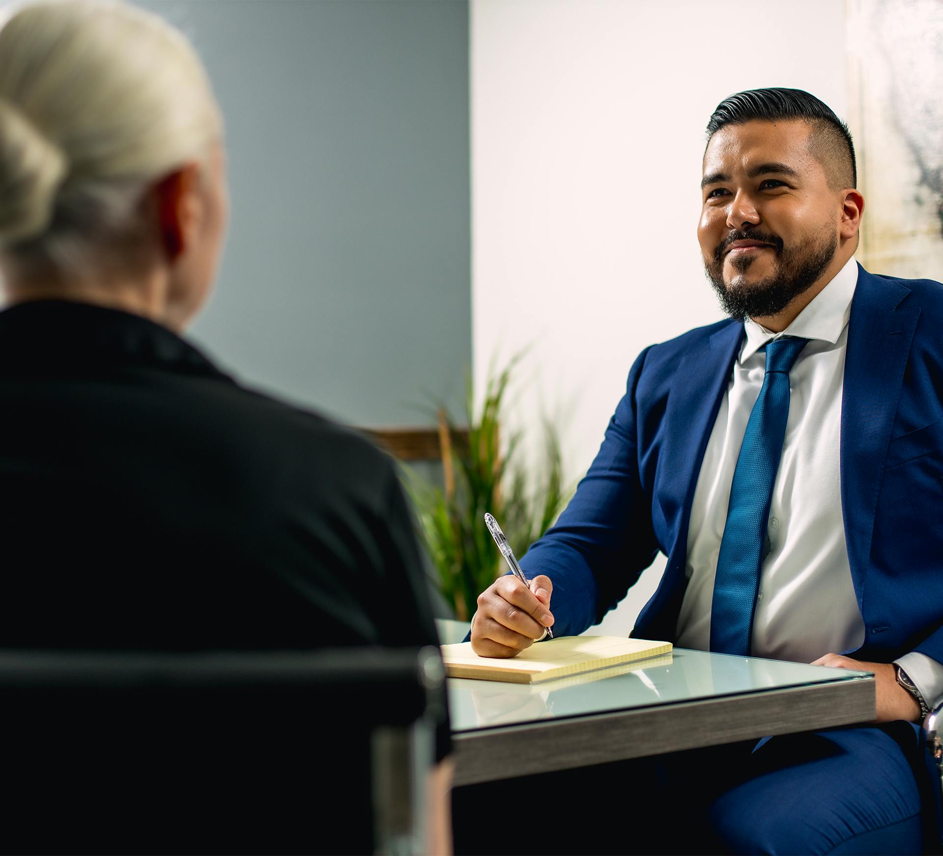Victor Cruz with Fiore Legal Injury Attorneys in a blue suit sitting at a table with a client