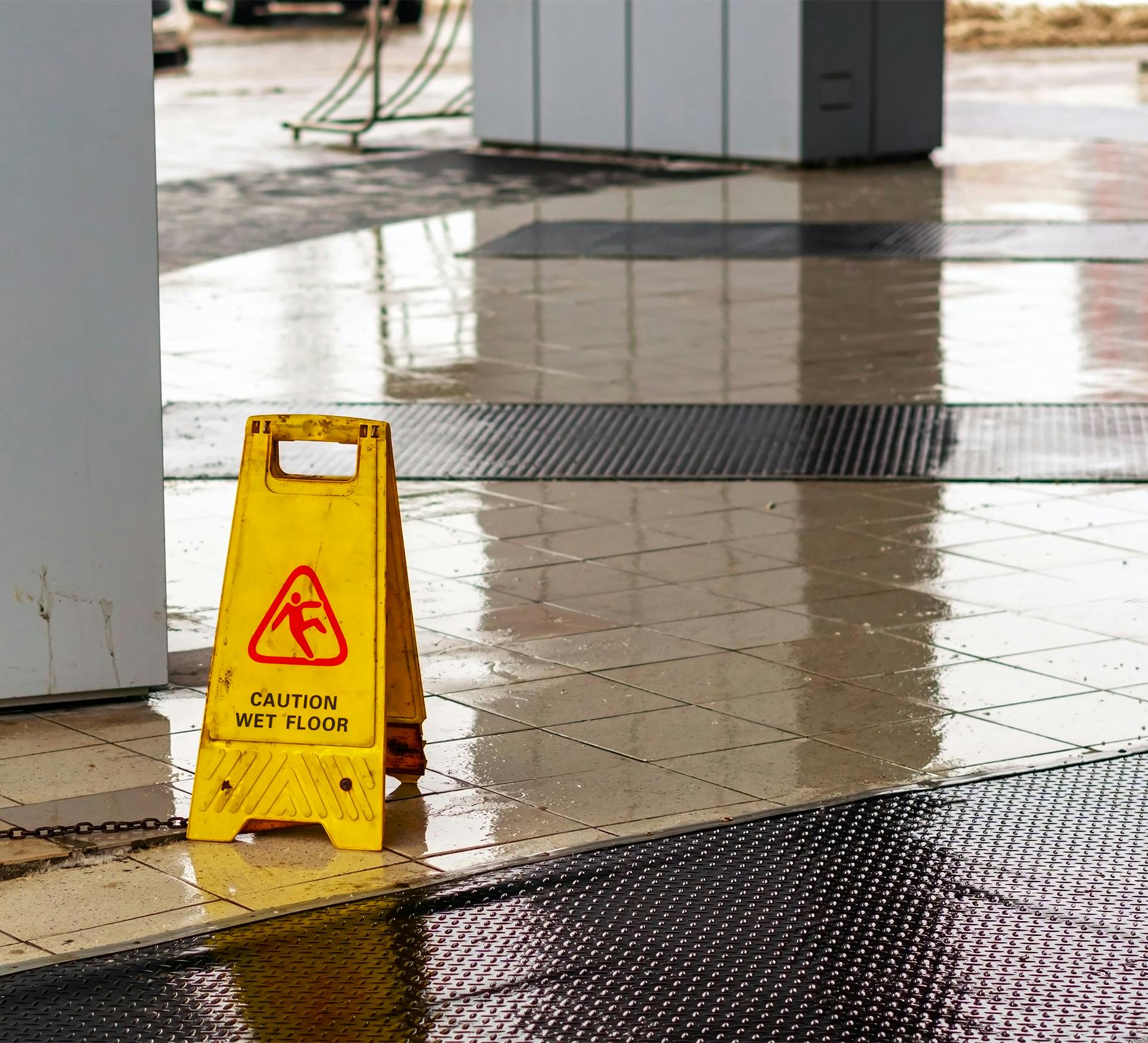 a wet floor sign outside a office building where the ground is wet