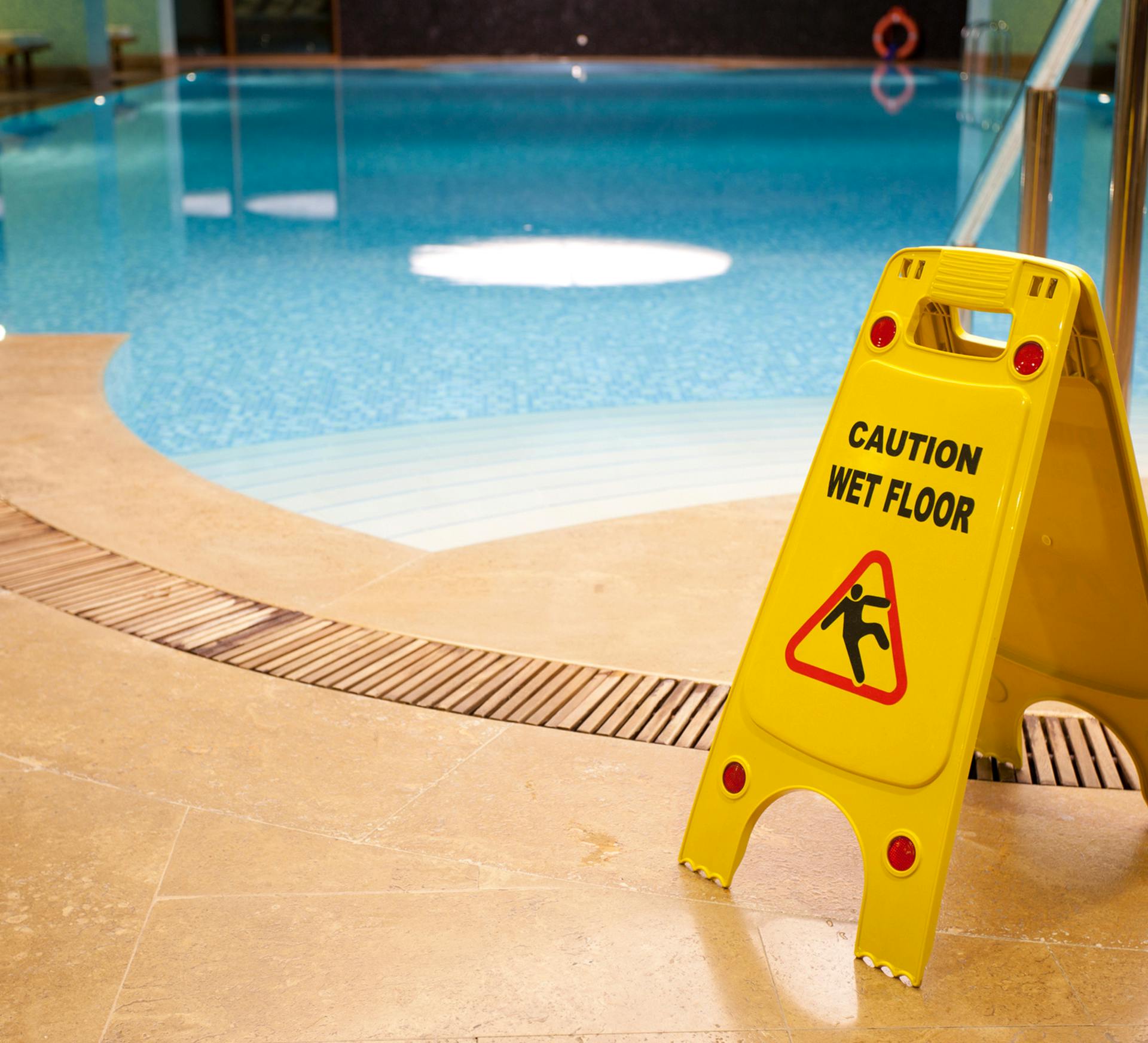 yellow caution wet floor sign next to a pool