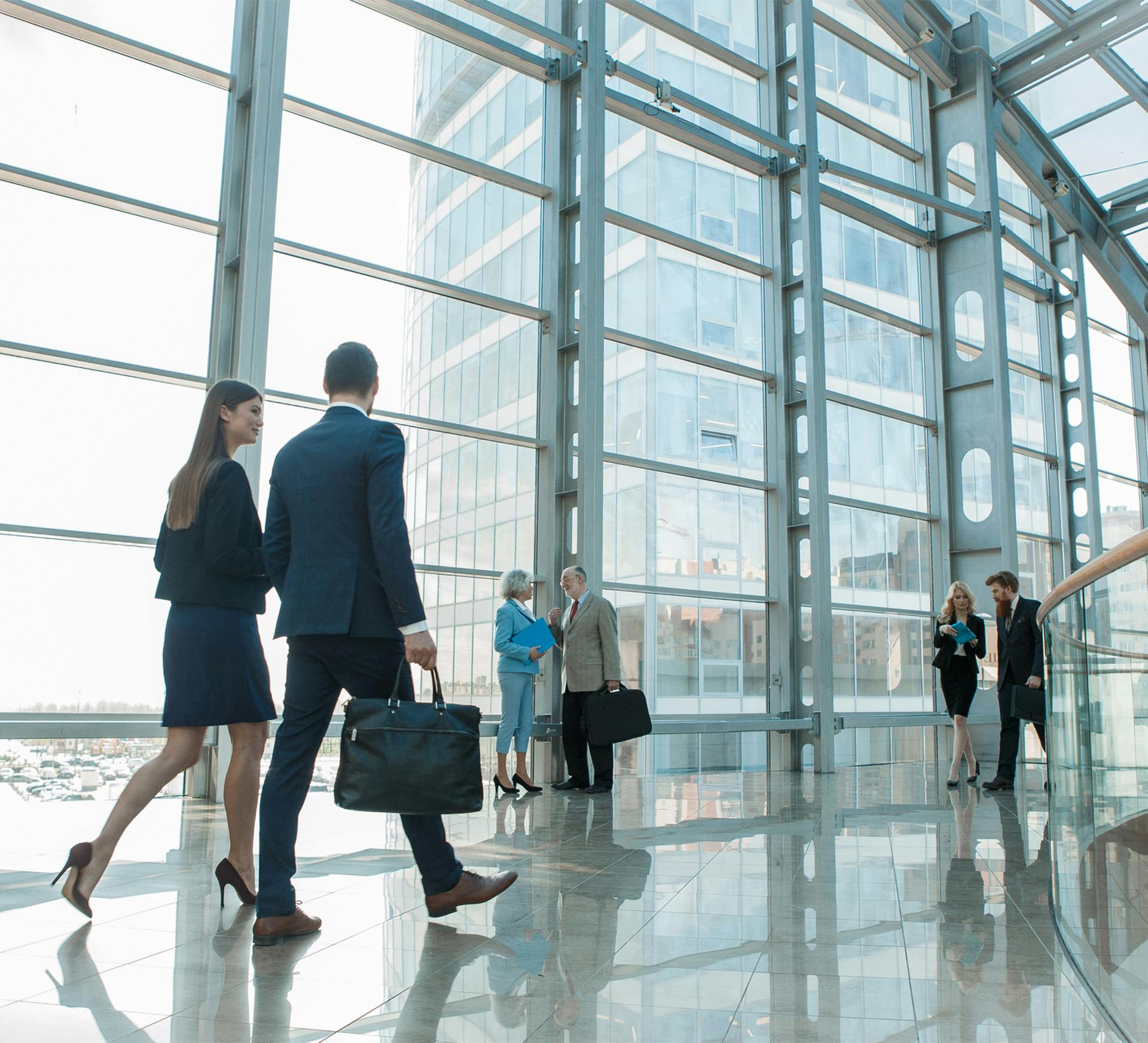 people walking in a large building with a glass wall