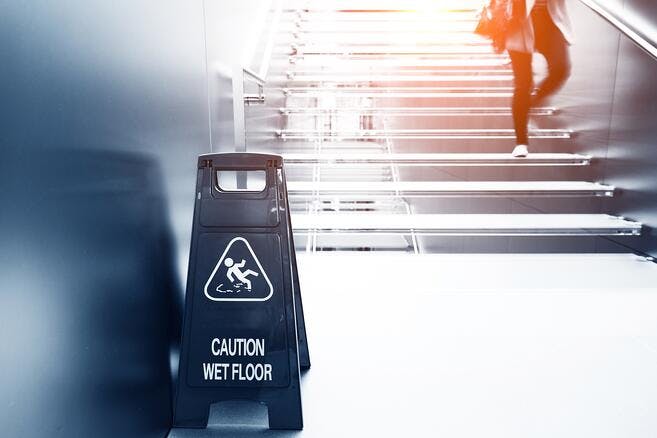 there is a sign that says caution wet floor while a person is walking down the stairs
