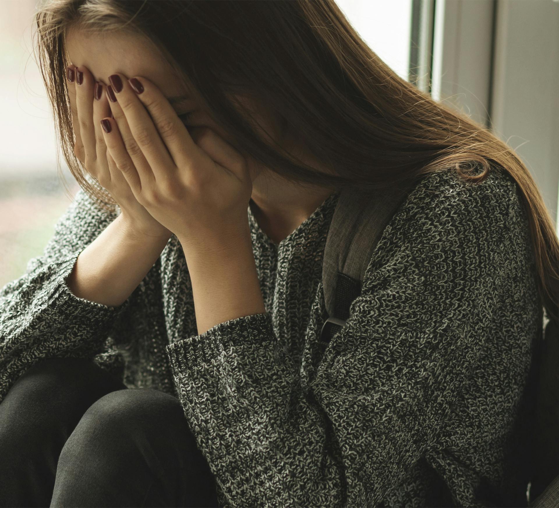 woman sitting on a couch with her hands covering her face