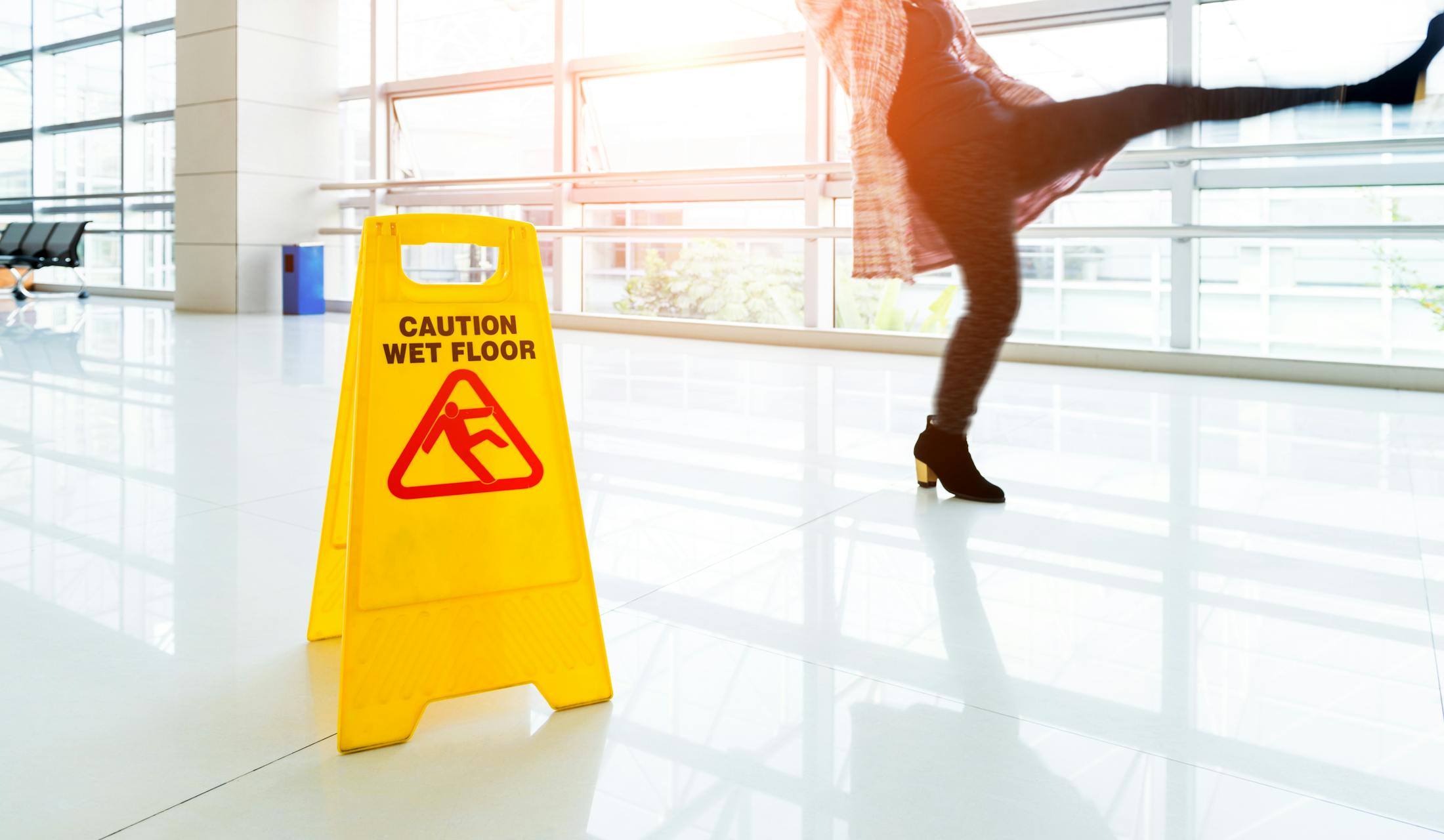 Person slipping and falling next to a caution sign