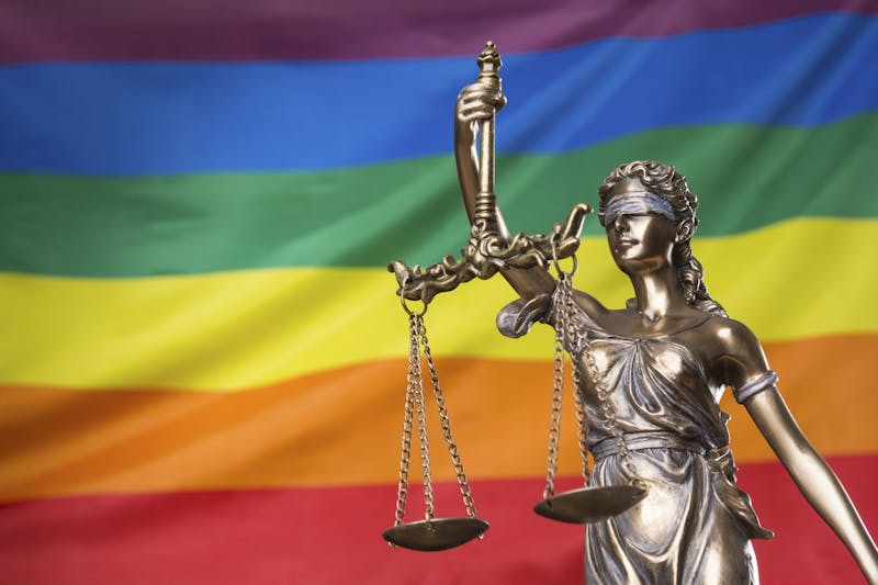 statue of Themis against the rainbow flag of LGBT community