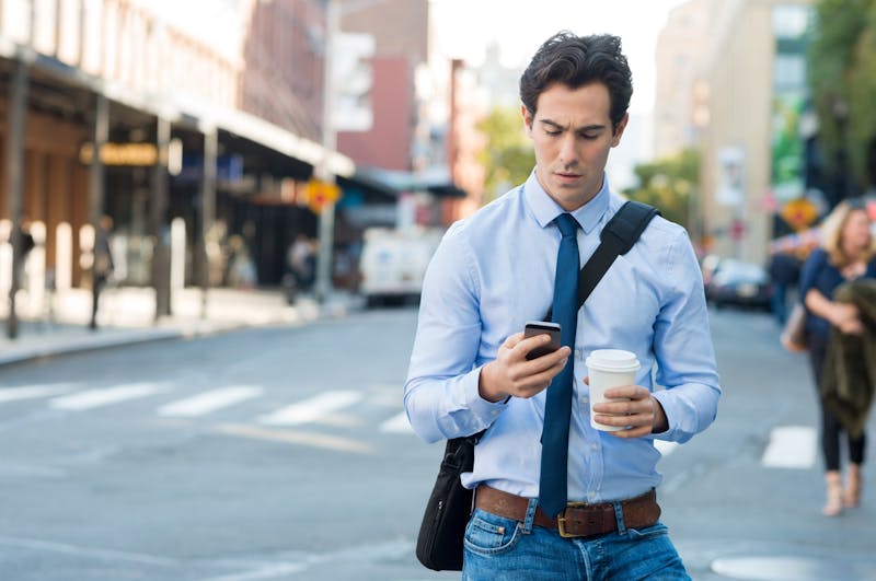 Man texting on smartphone while walking in the city