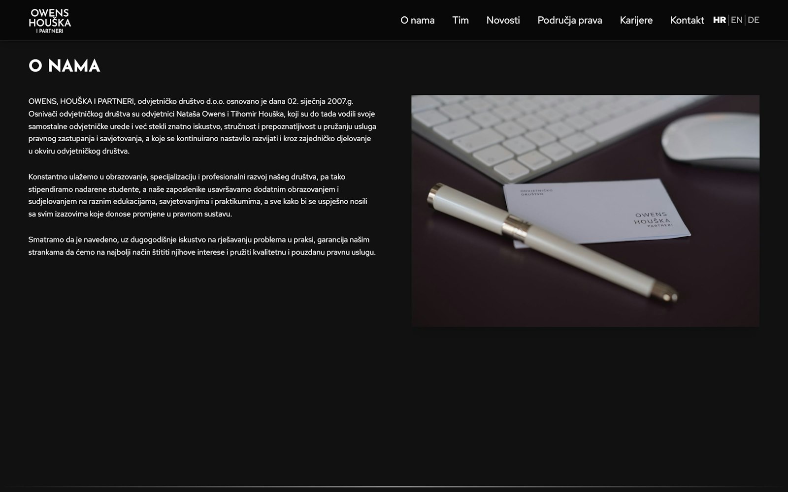About page on a dark background with the firm's history next to a photo of a pen and business card.
