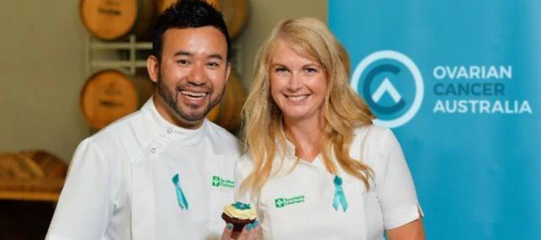 Man and woman in white holding a cupcake
